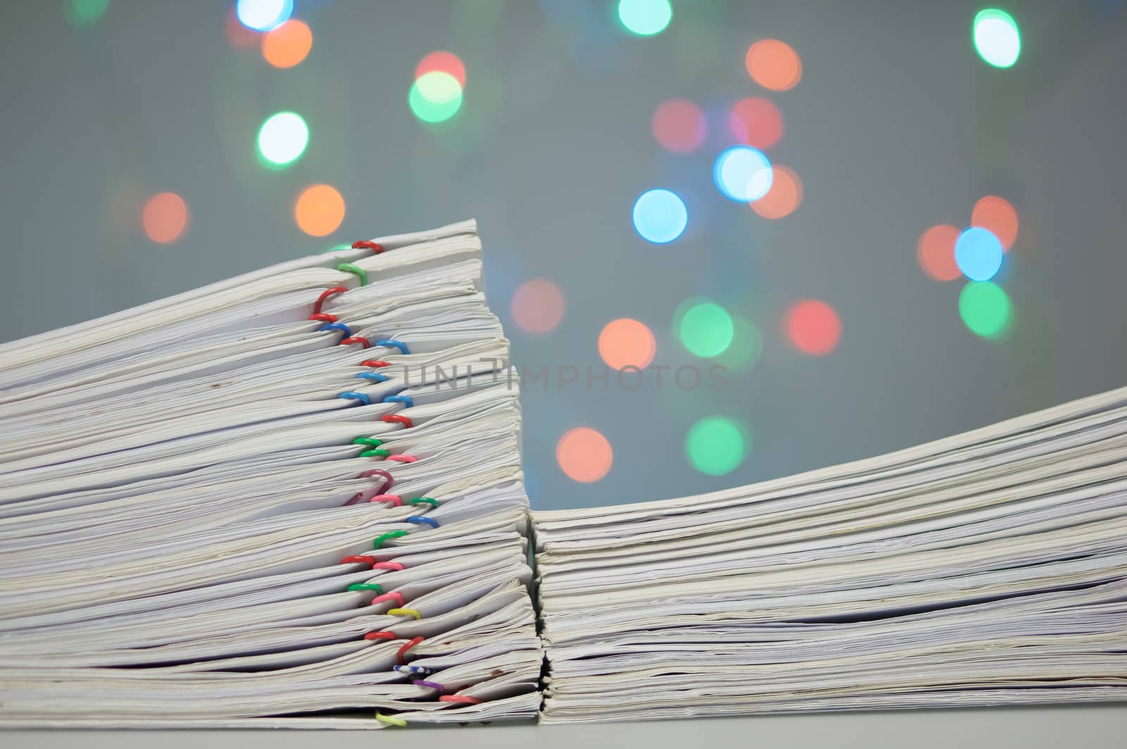 Pile of paperwork with colorful paperclip have colorful bokeh circle or defocused of glitter as background.