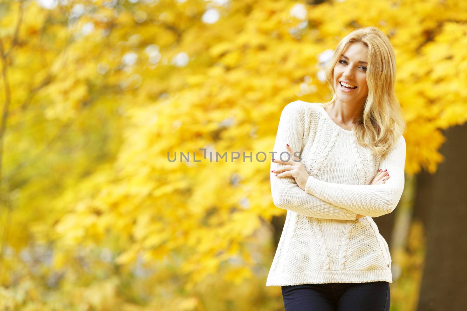 Happy woman posing in autumn park on yellow trees background