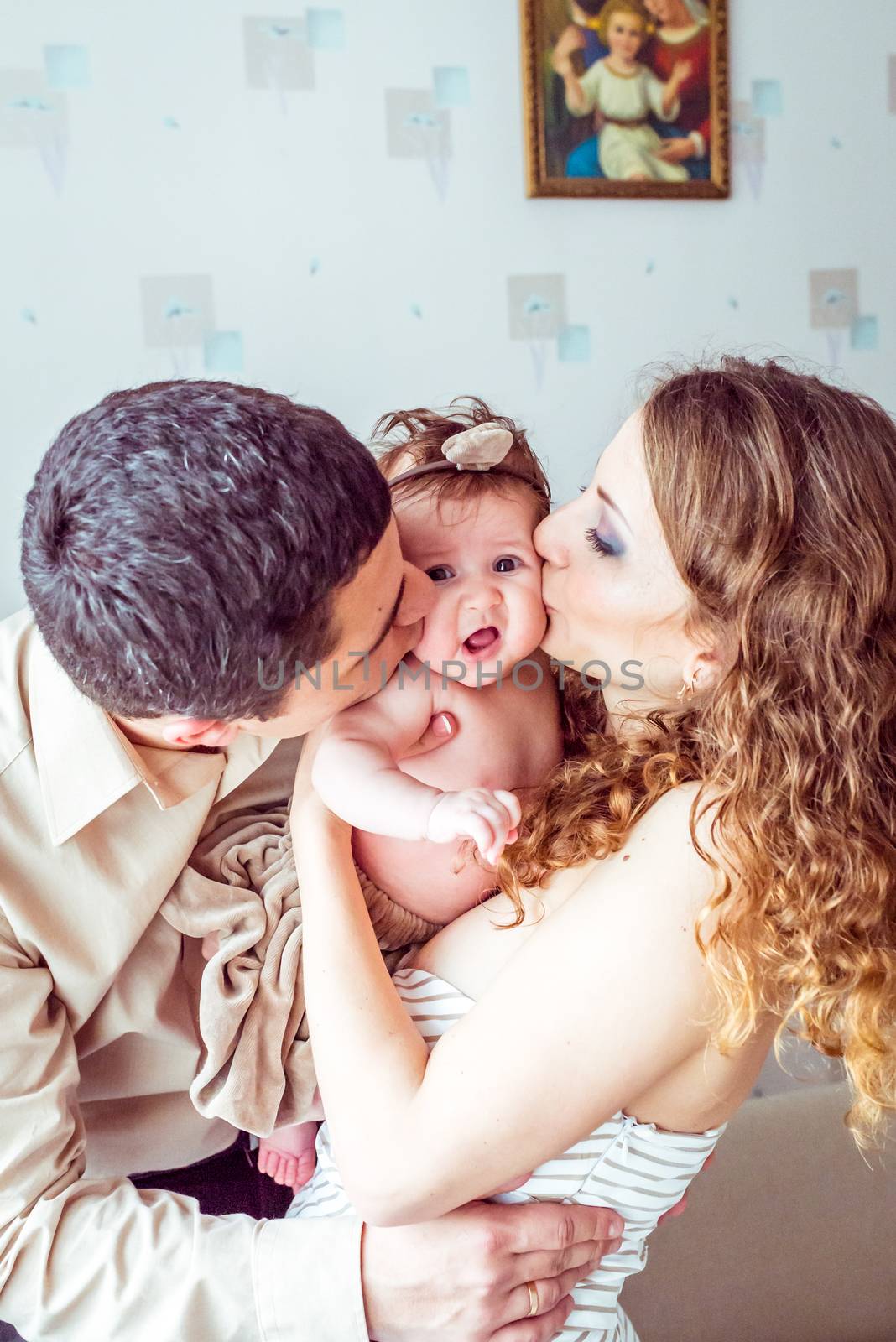 Happy parents kiss the baby by okskukuruza