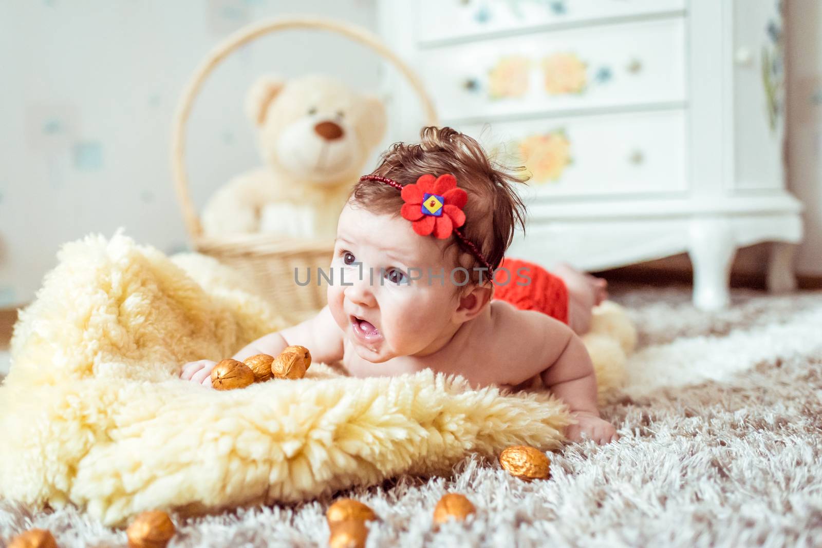 naked baby lying on a yellow soft blanket with decorated golden nuts in the room