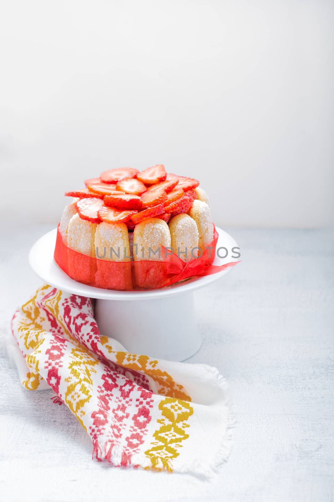 Yogurt strawberry cake with savoiardi biscuits on a white plate