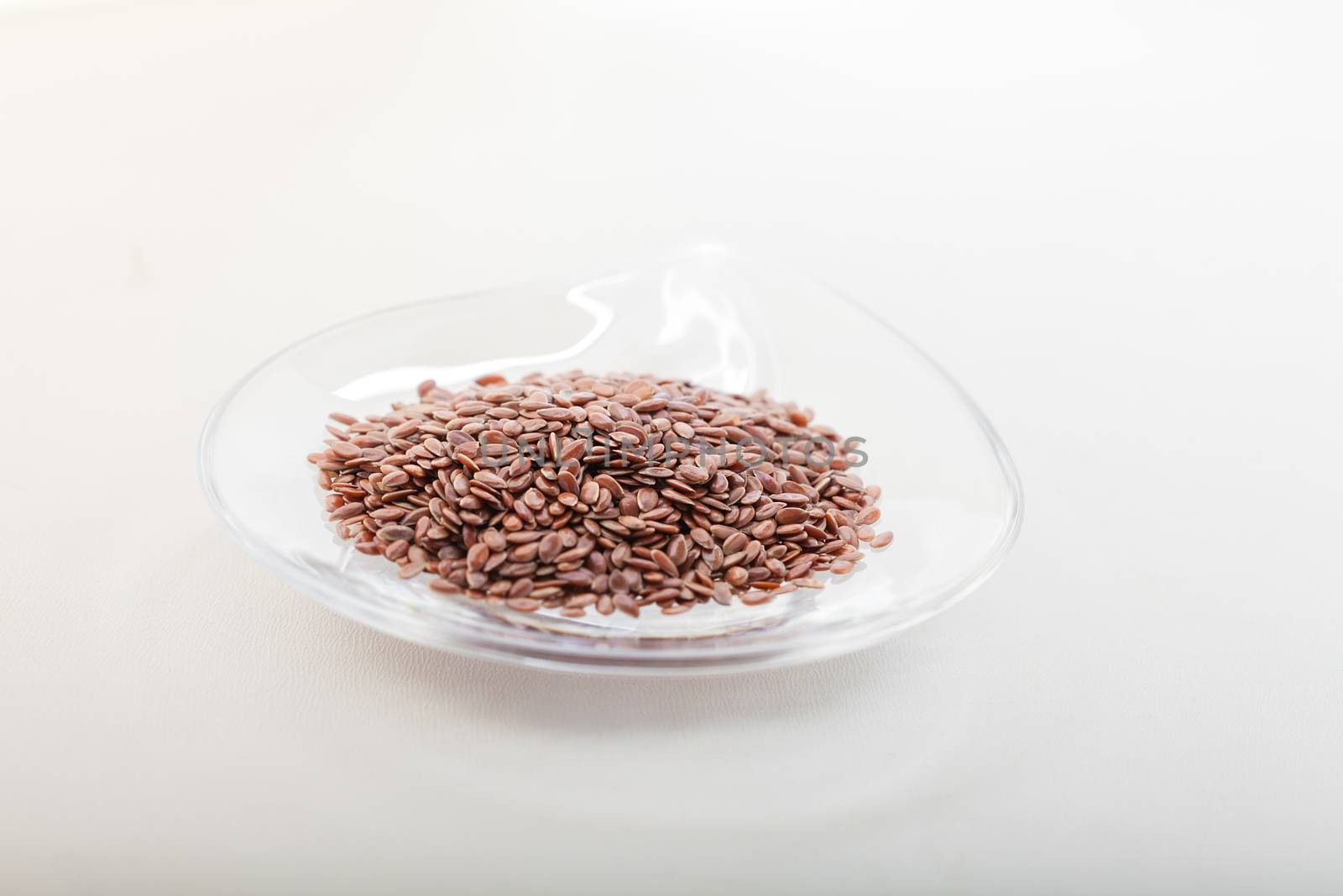 Flax seed in glass bowl on a white surface