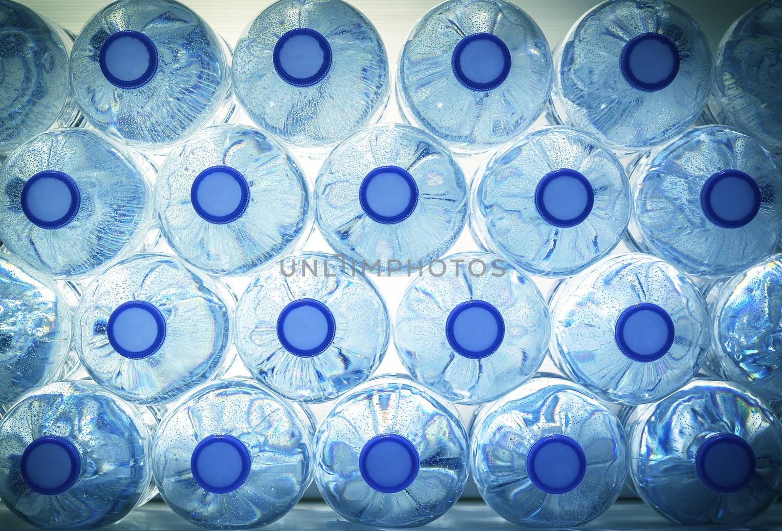 Rows of water in plastic bottles on blue background