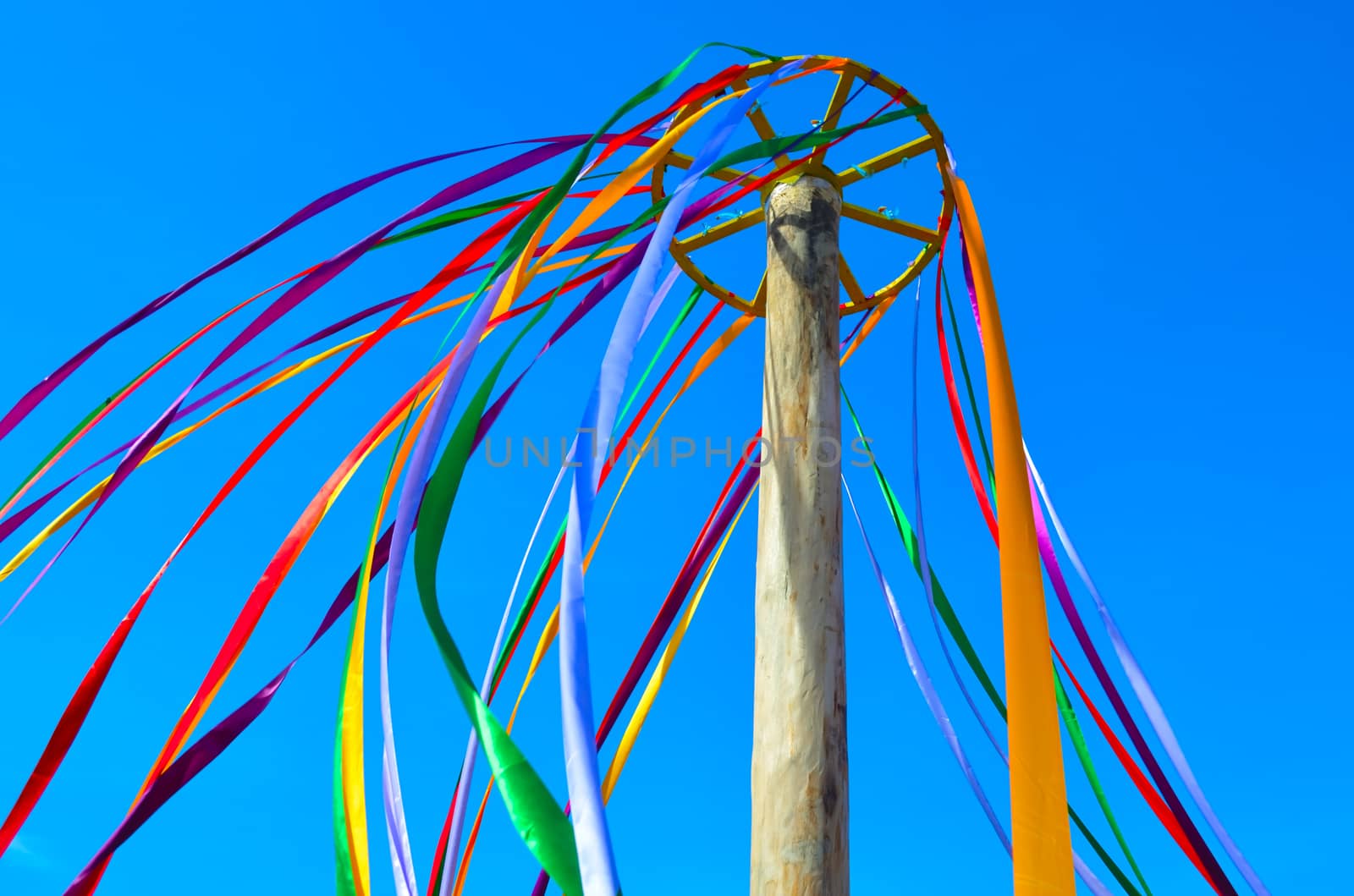 Multi-colored ribbons on a pole waving in the wind against the blue sky