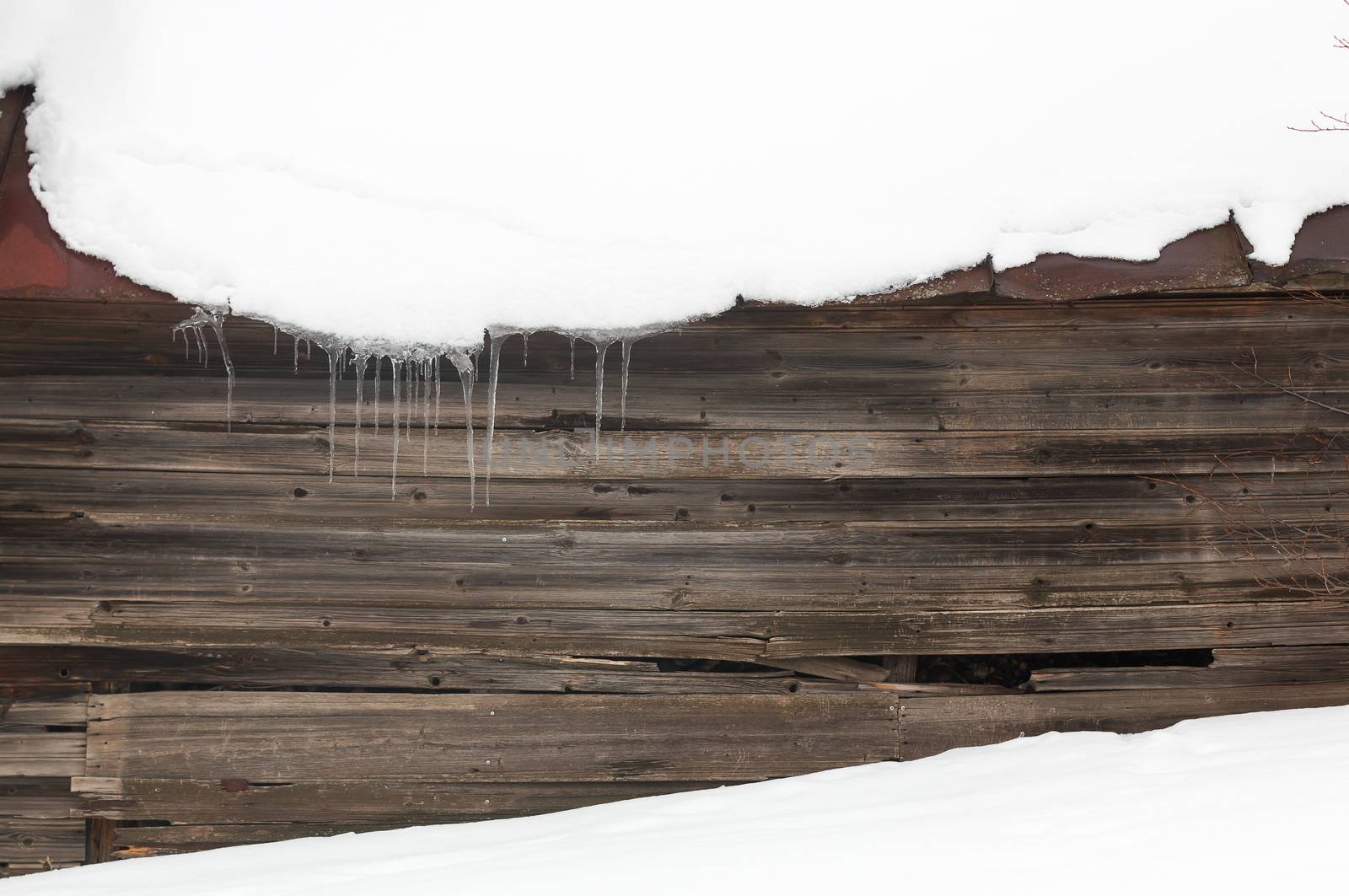 Ice and icicles with snow on a dark wooden background, contrasting winter backdrop.