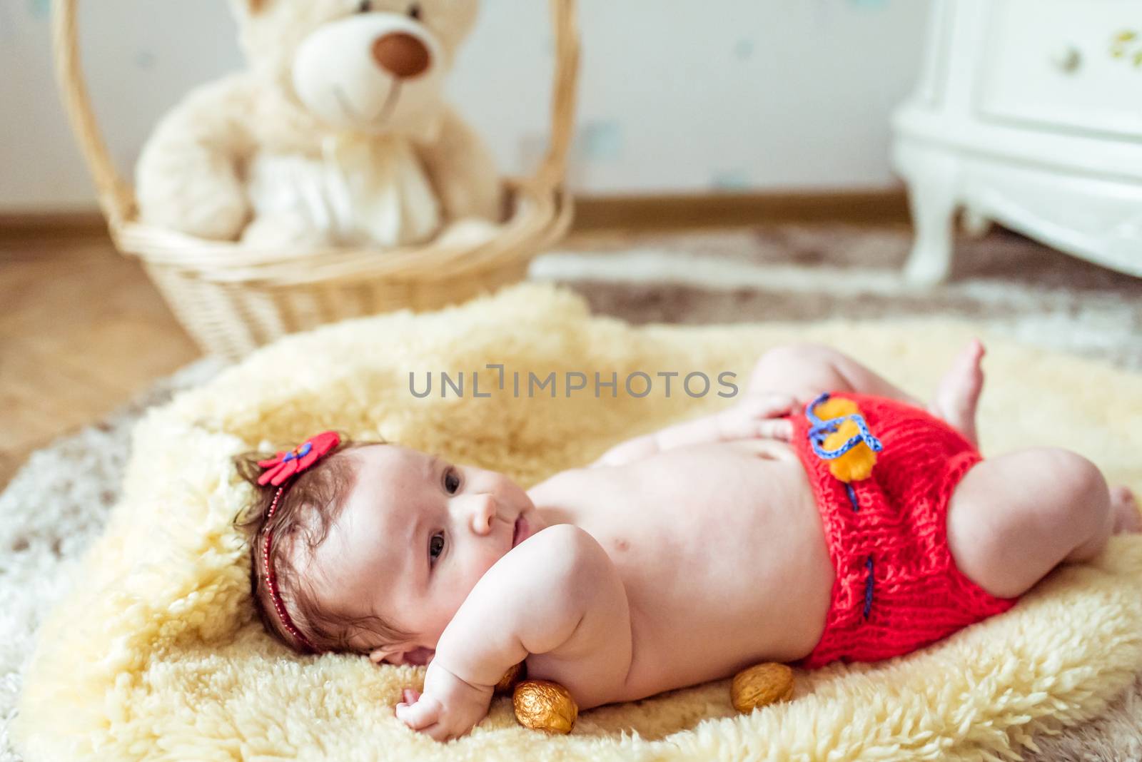 naked baby lying on a yellow soft blanket with decorated golden nuts in the room