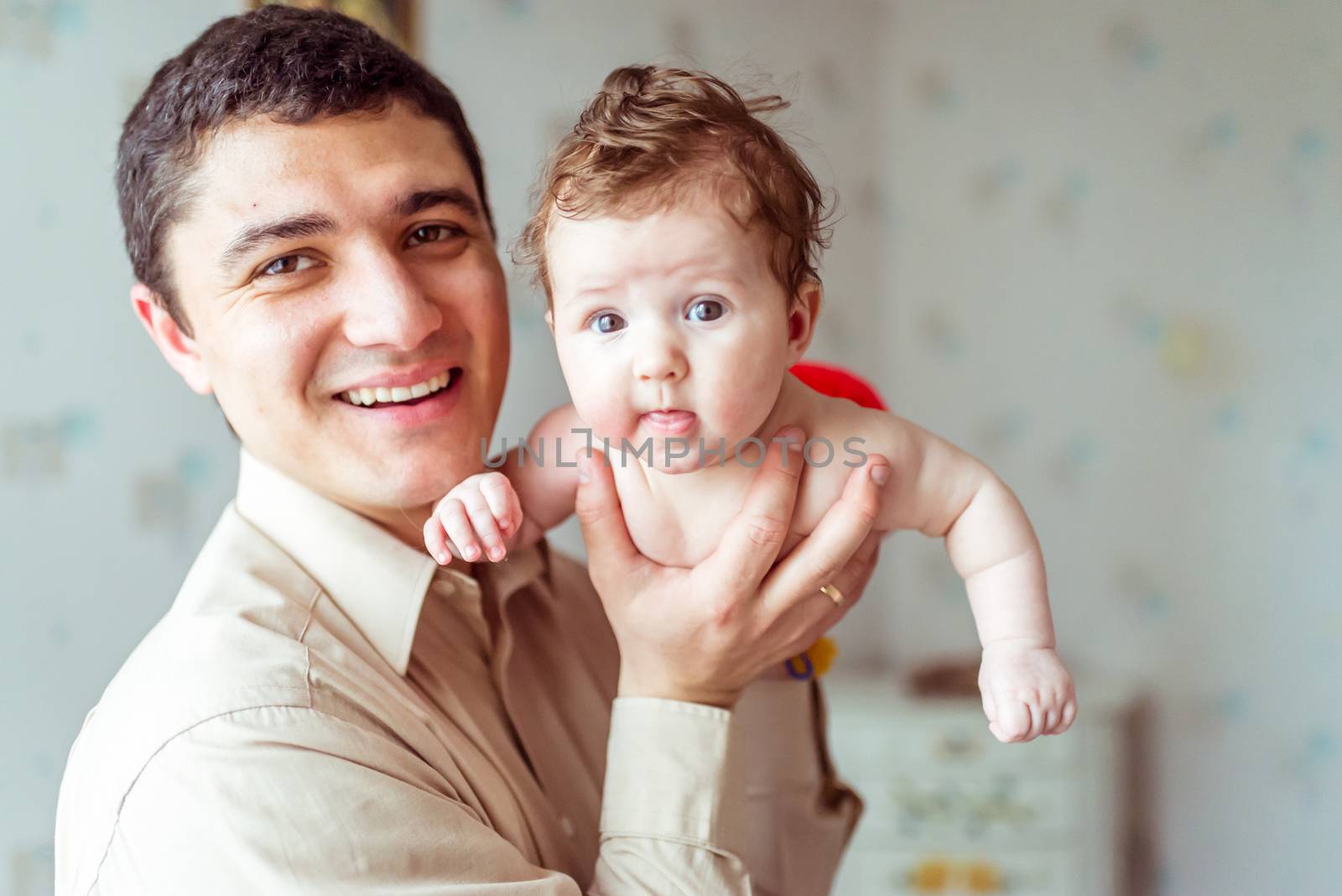 happy father holds on hands naked baby in a room