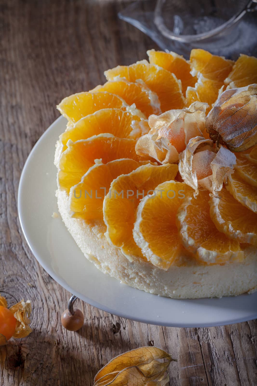 Cheesecake decorated with oranges and physalis on a