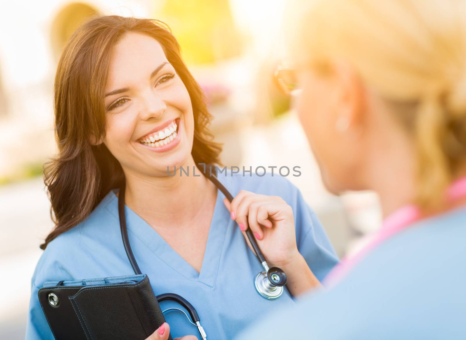 Two Young Adult Professional Female Doctors or Nurses Talking Outside.