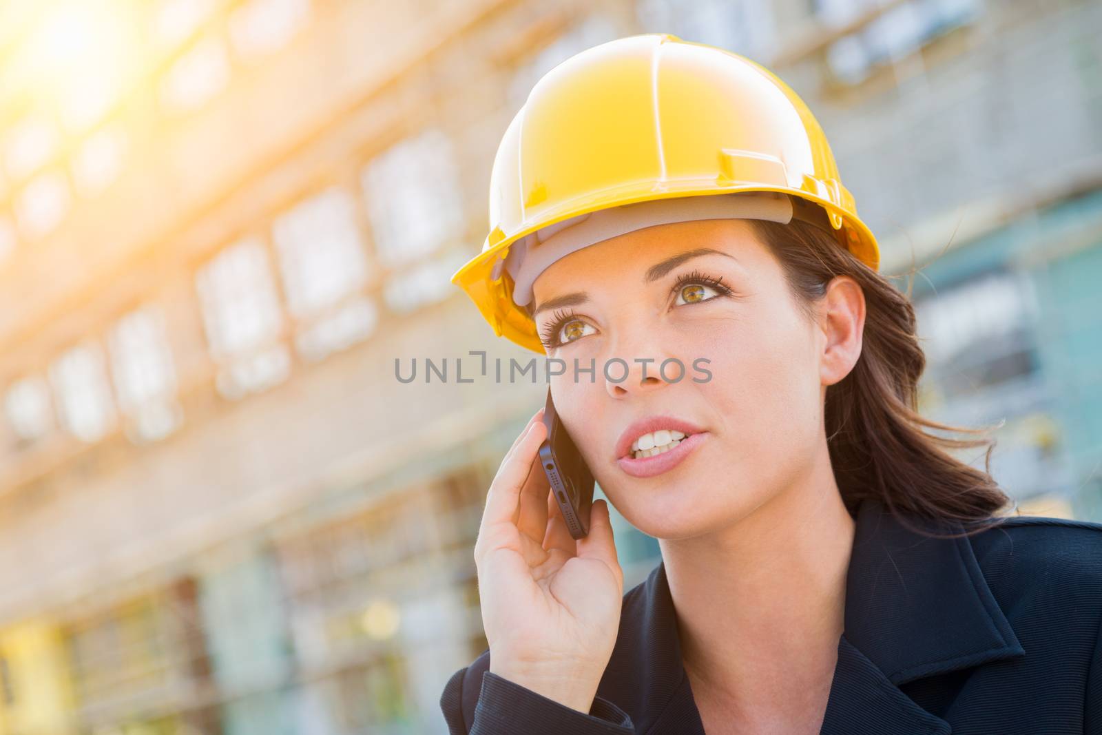 Young Professional Female Contractor Wearing Hard Hat at Construction Site Using Cell Phone.