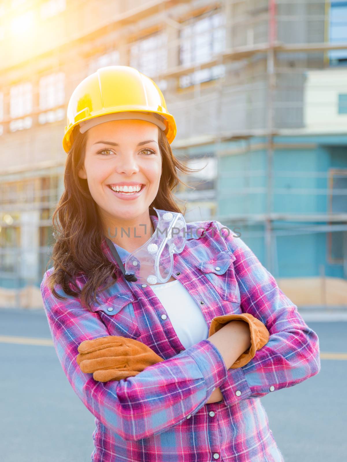 Portrait of Young Female Construction Worker Wearing Gloves, Hard Hat and Protective Goggles at Construction Site.