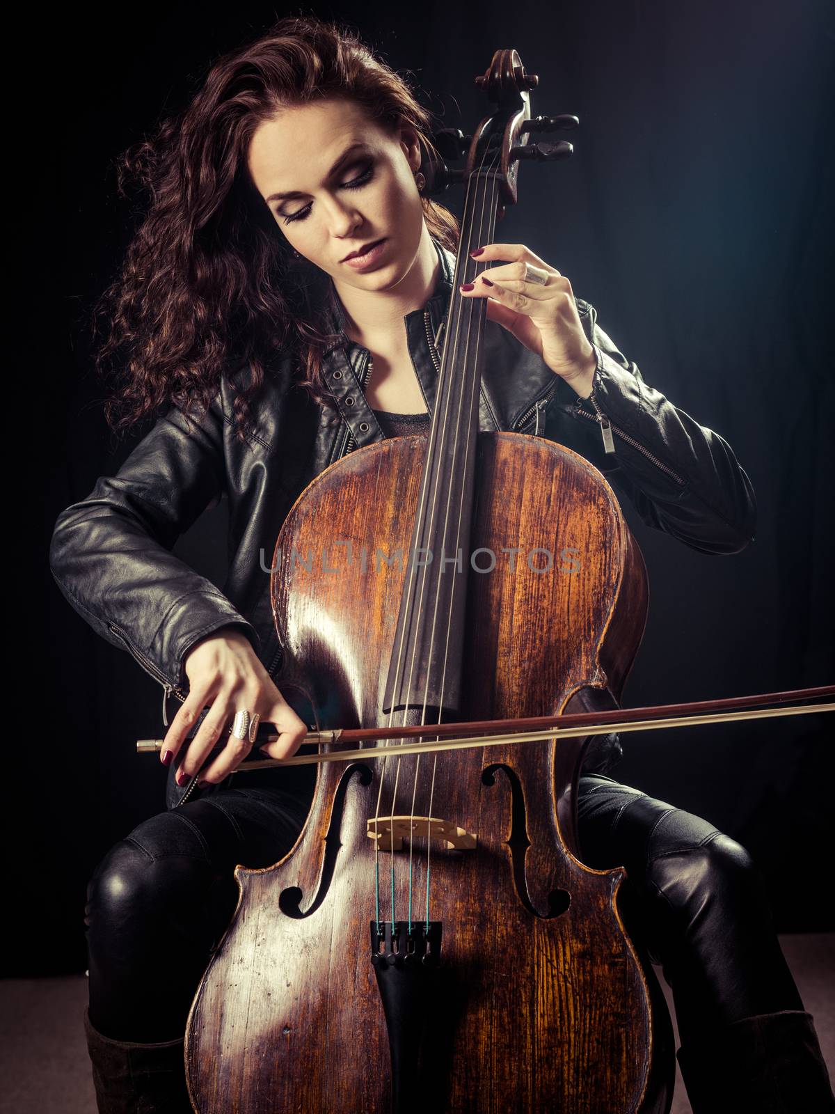 Photo of a beautiful female musician playing a cello.