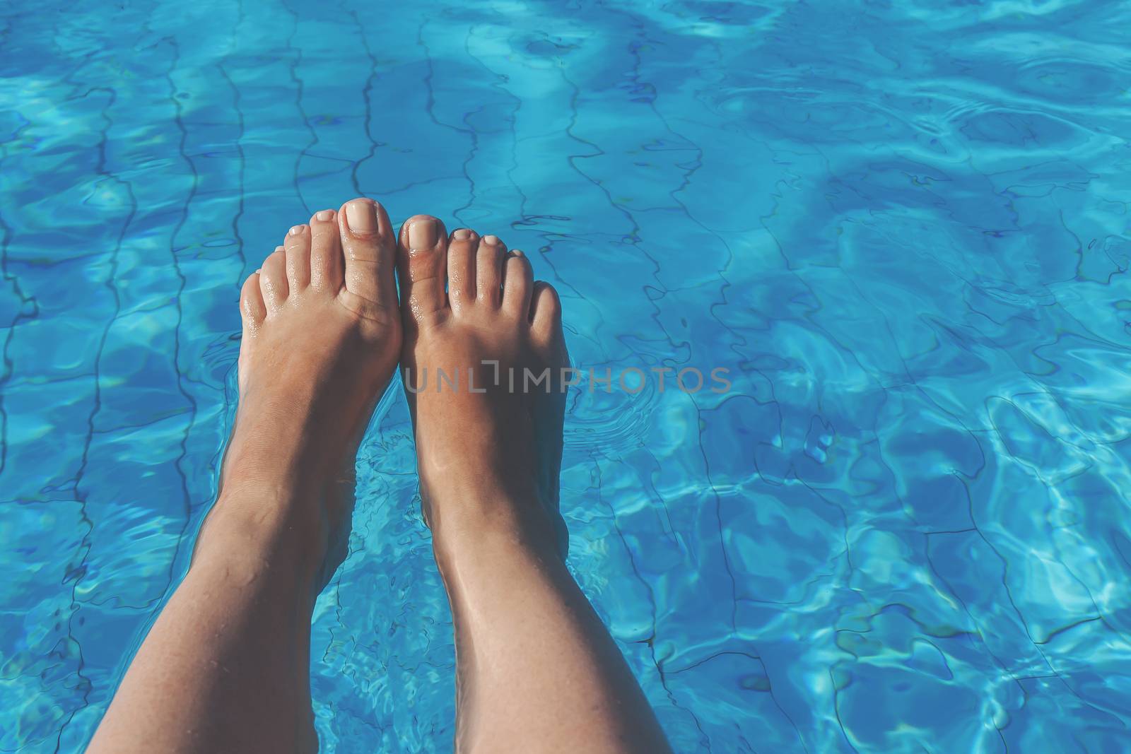 naked female legs on a background of blue water.