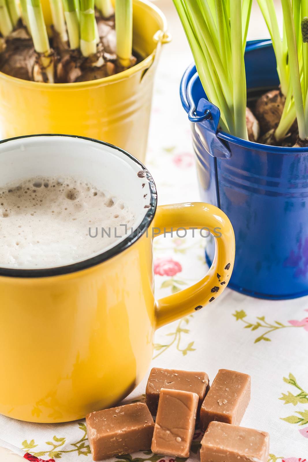 on a tray with a yellow cup of coffee, toffee and a bucket of flowers with bulbs