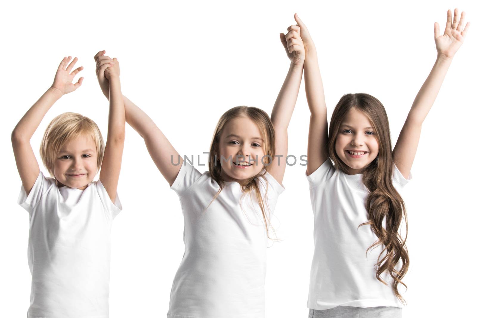 Happy smiling three children in white clothes holding raised hands isolated on white background