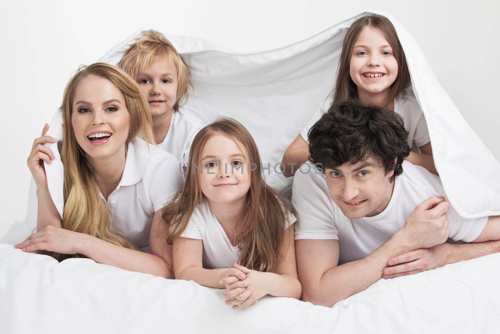 Smiling family with three children wake up in bed