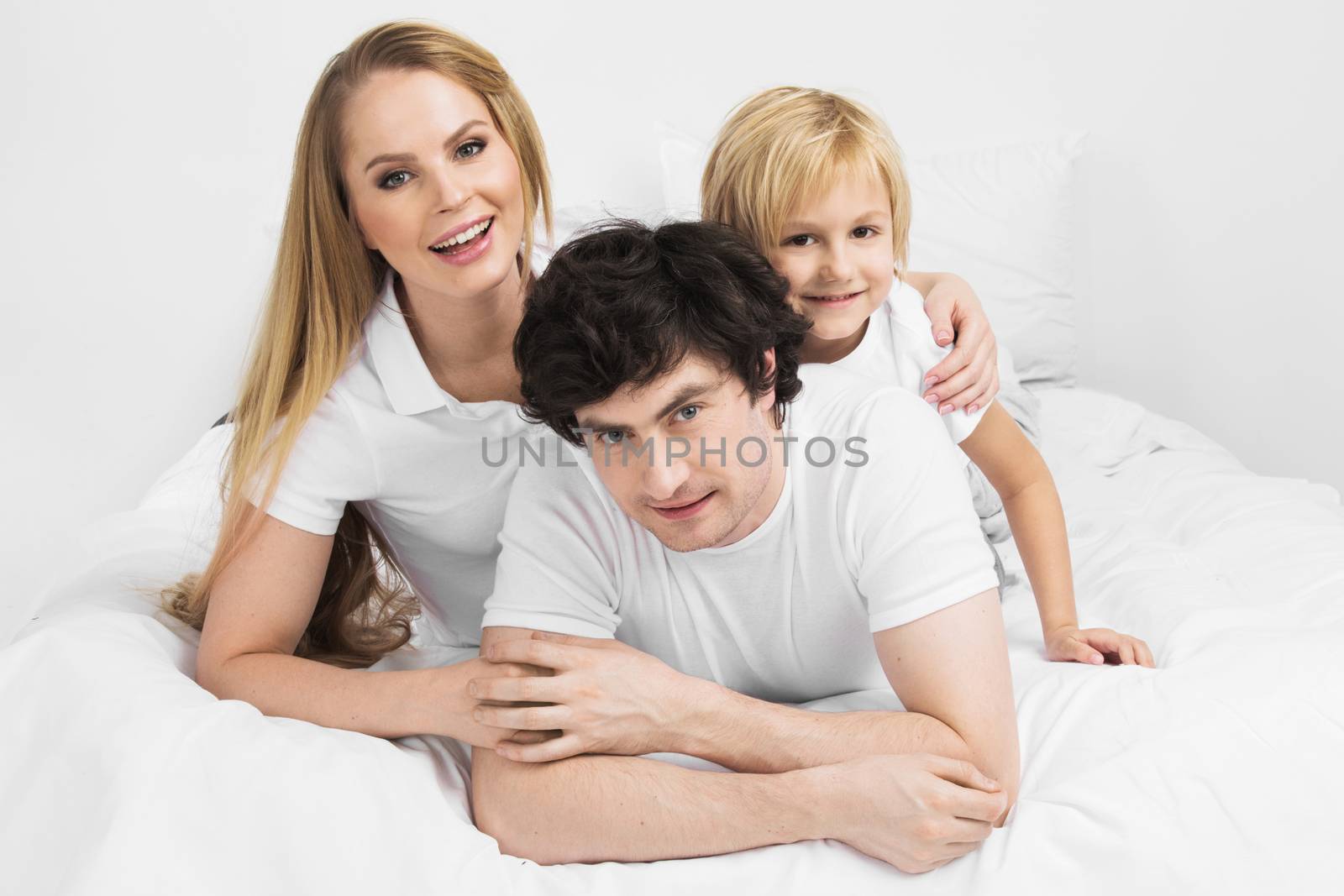 Smiling family with child wake up in bed