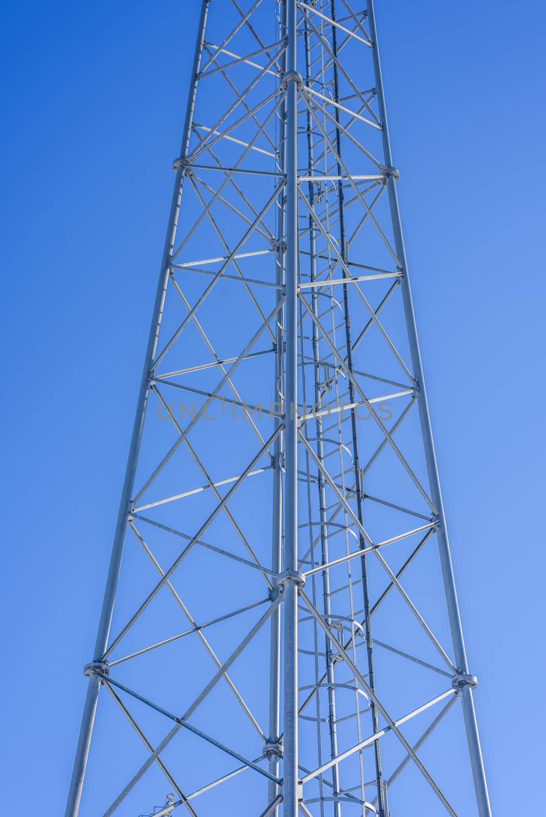Steel tower with ladder inside against a blue sky.