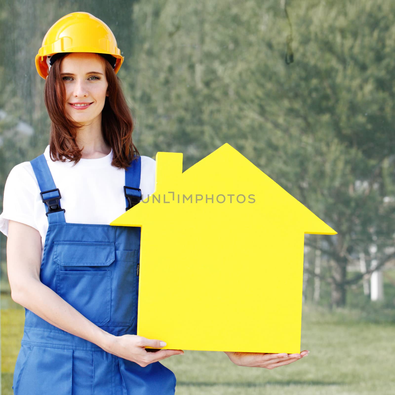 Happy smiling female worker in hardhat holding house model