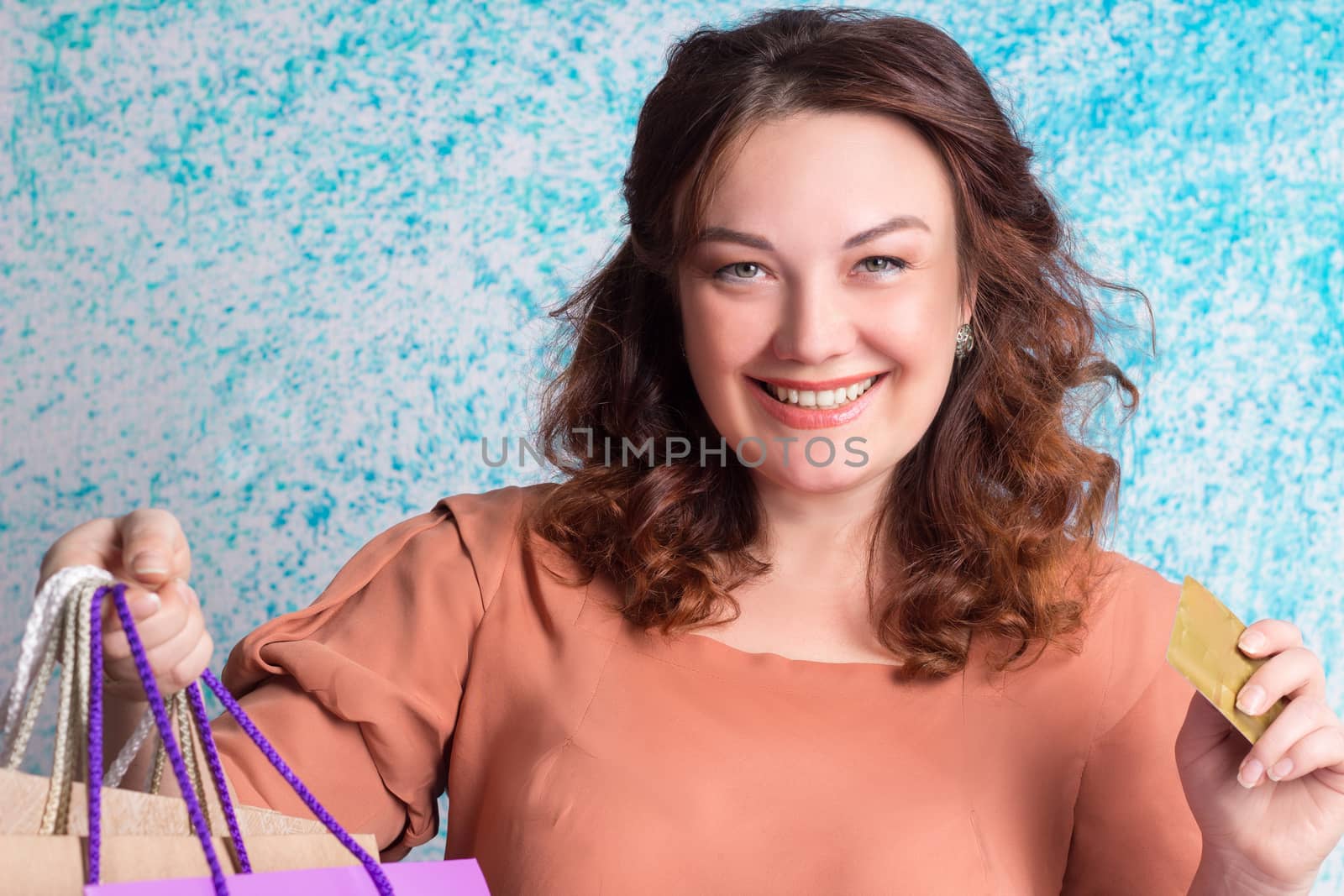 Happy smiling woman holding colourful shopping paper bags and banking credit card