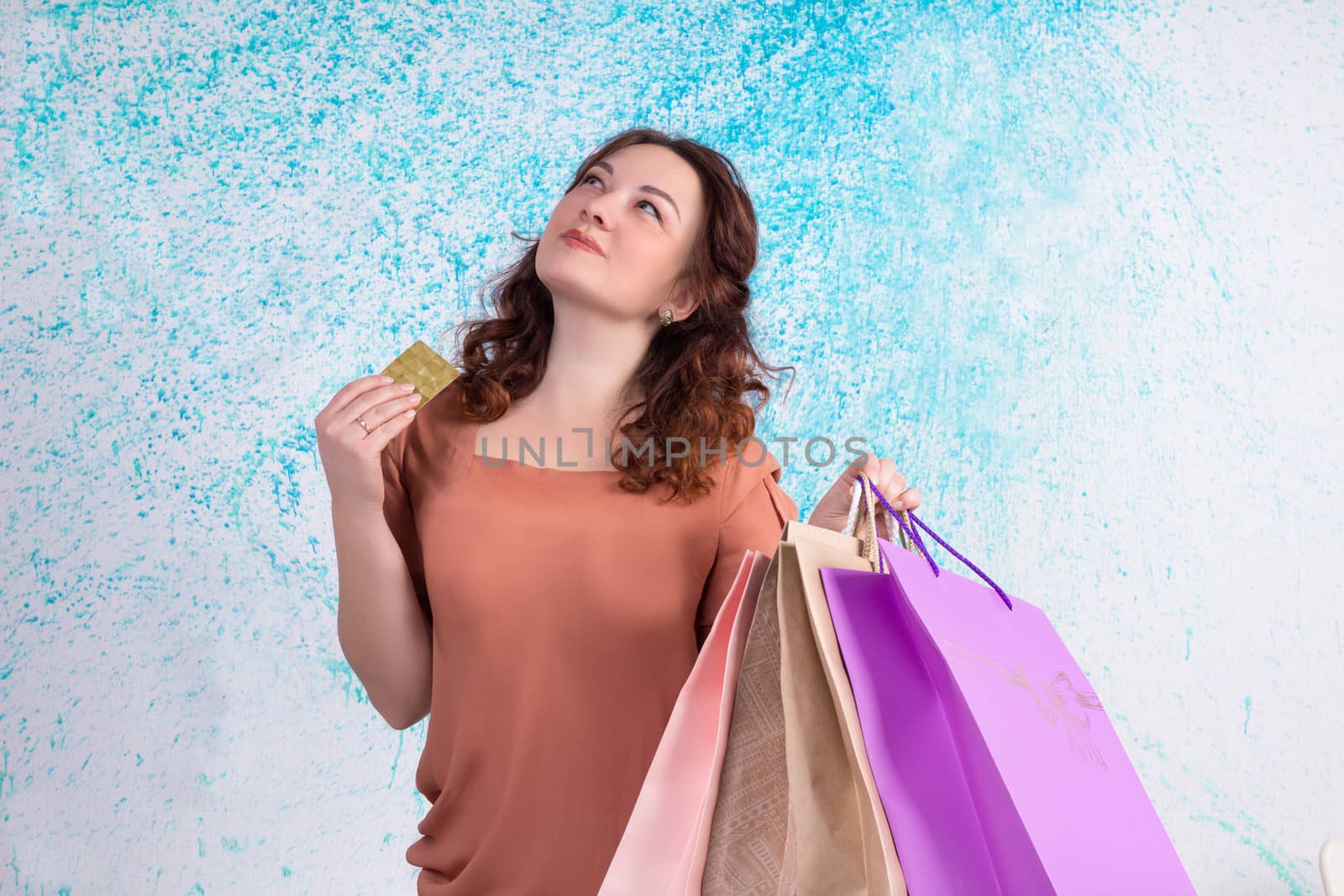 Happy smiling woman holding colourful shopping paper bags and banking credit card