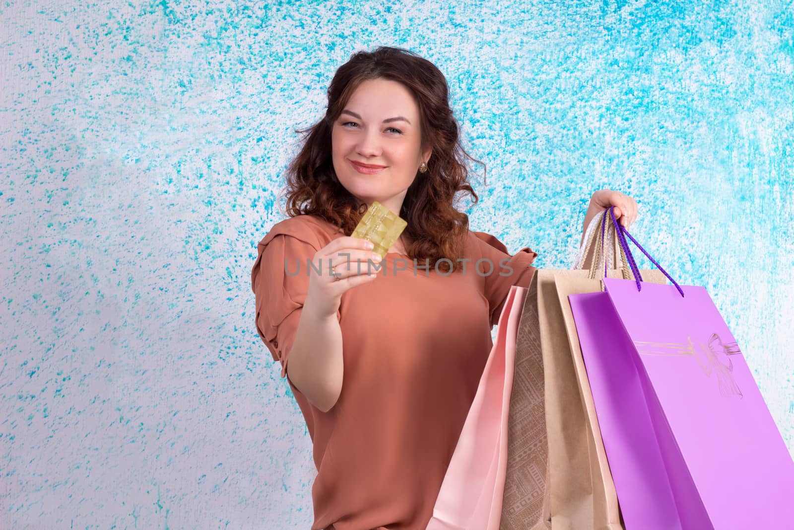 Happy smiling woman holding colourful shopping paper bags and banking credit card
