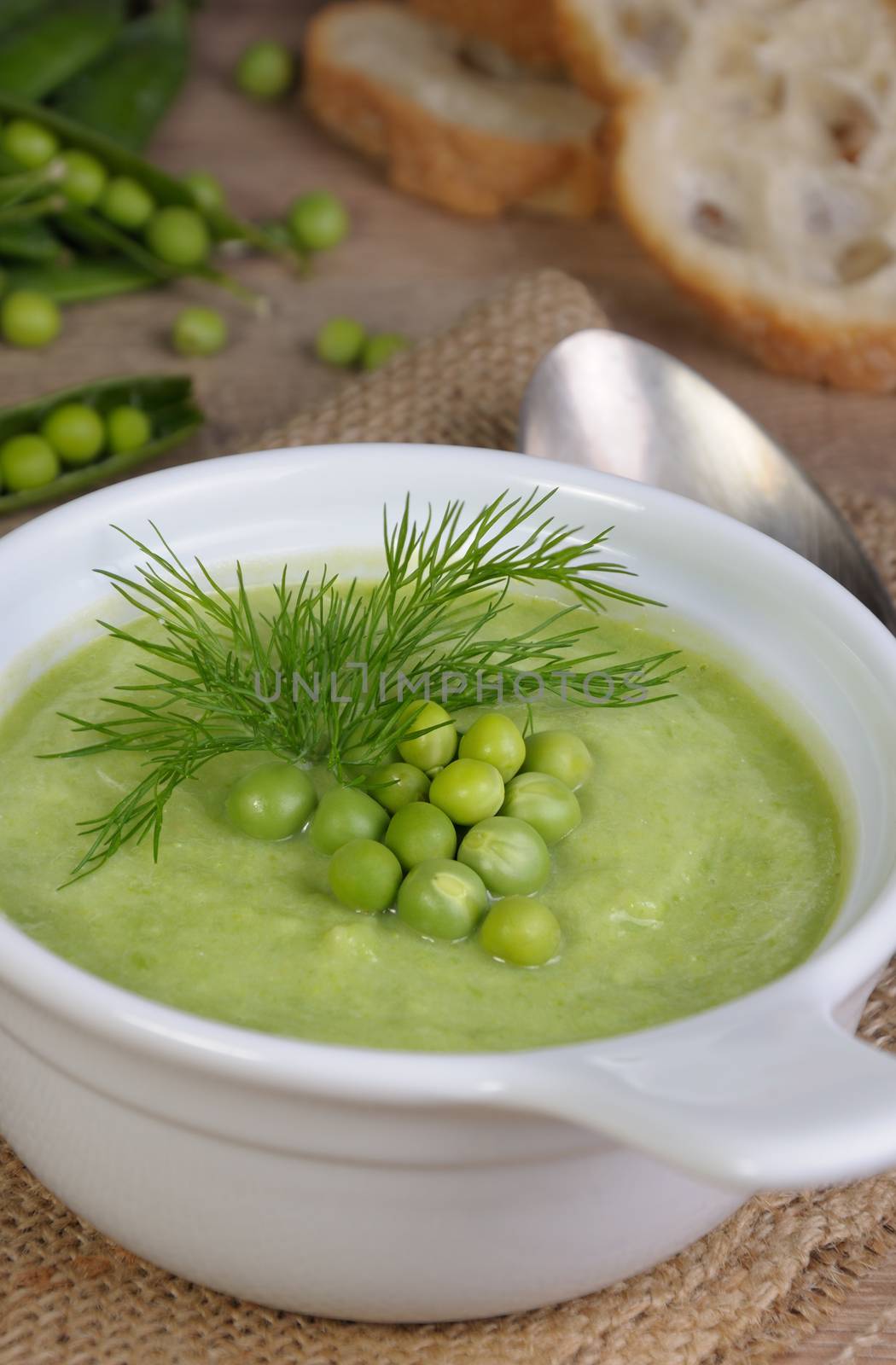 A plate of soup puree of green peas with dill on a table