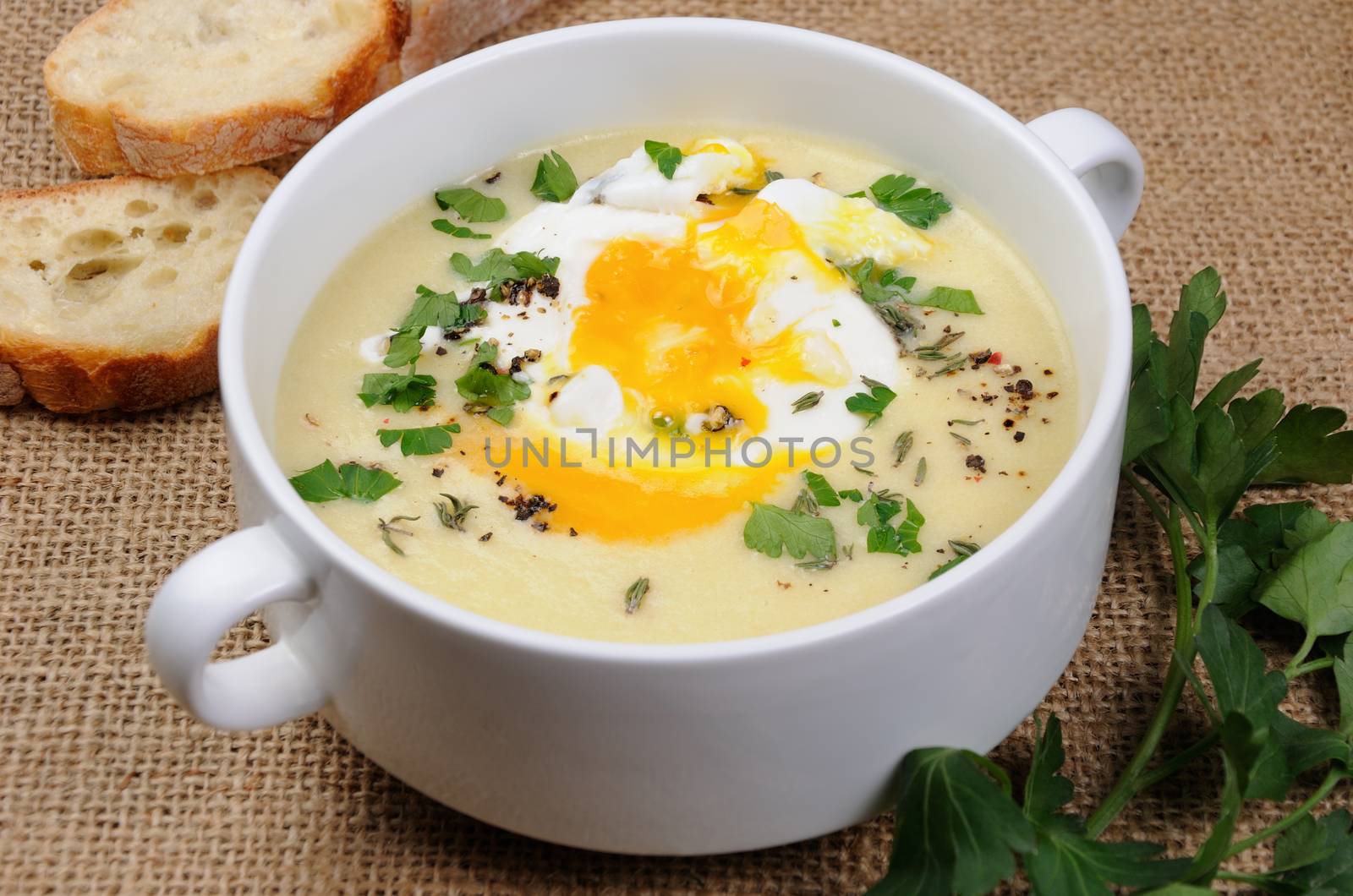 potato cream soup with bacon and poached eggs, herbs, spices