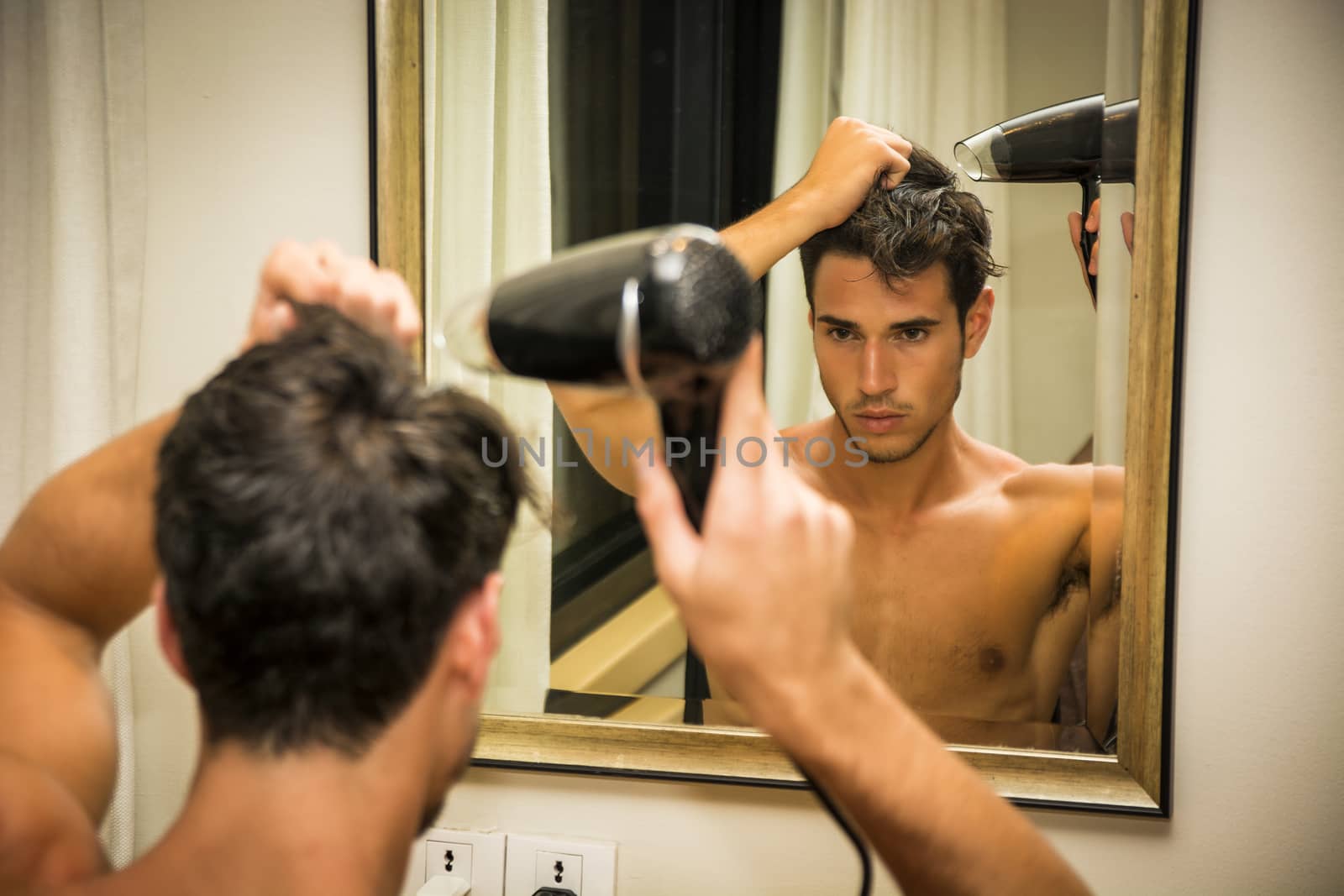 Shirtless young man drying hair with hairdryer by artofphoto
