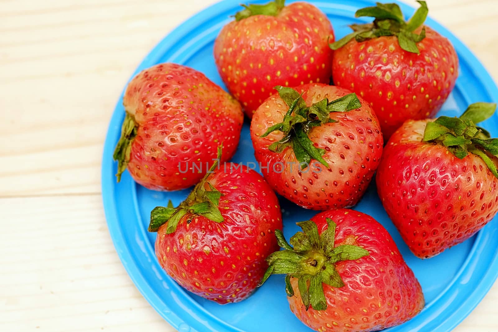 Red Strawberry Group in Blue Dish on the Table Wood