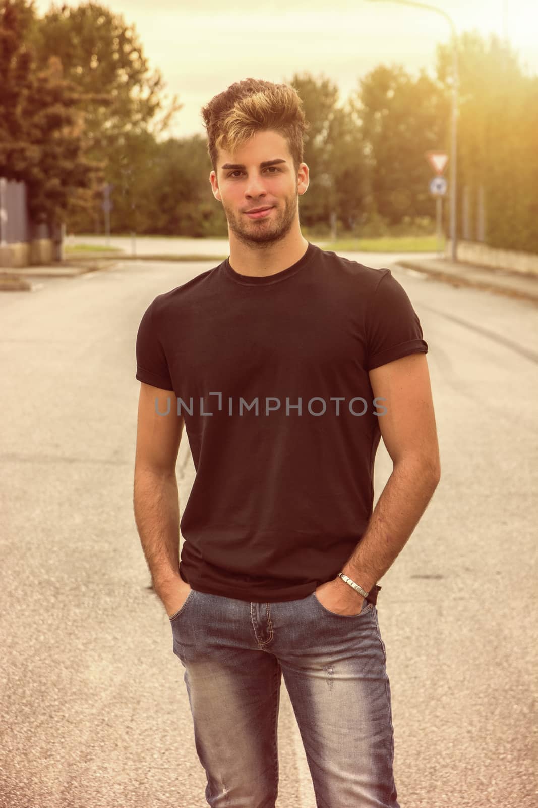 Attractive smiling man standing in the middle of city street looking at camera