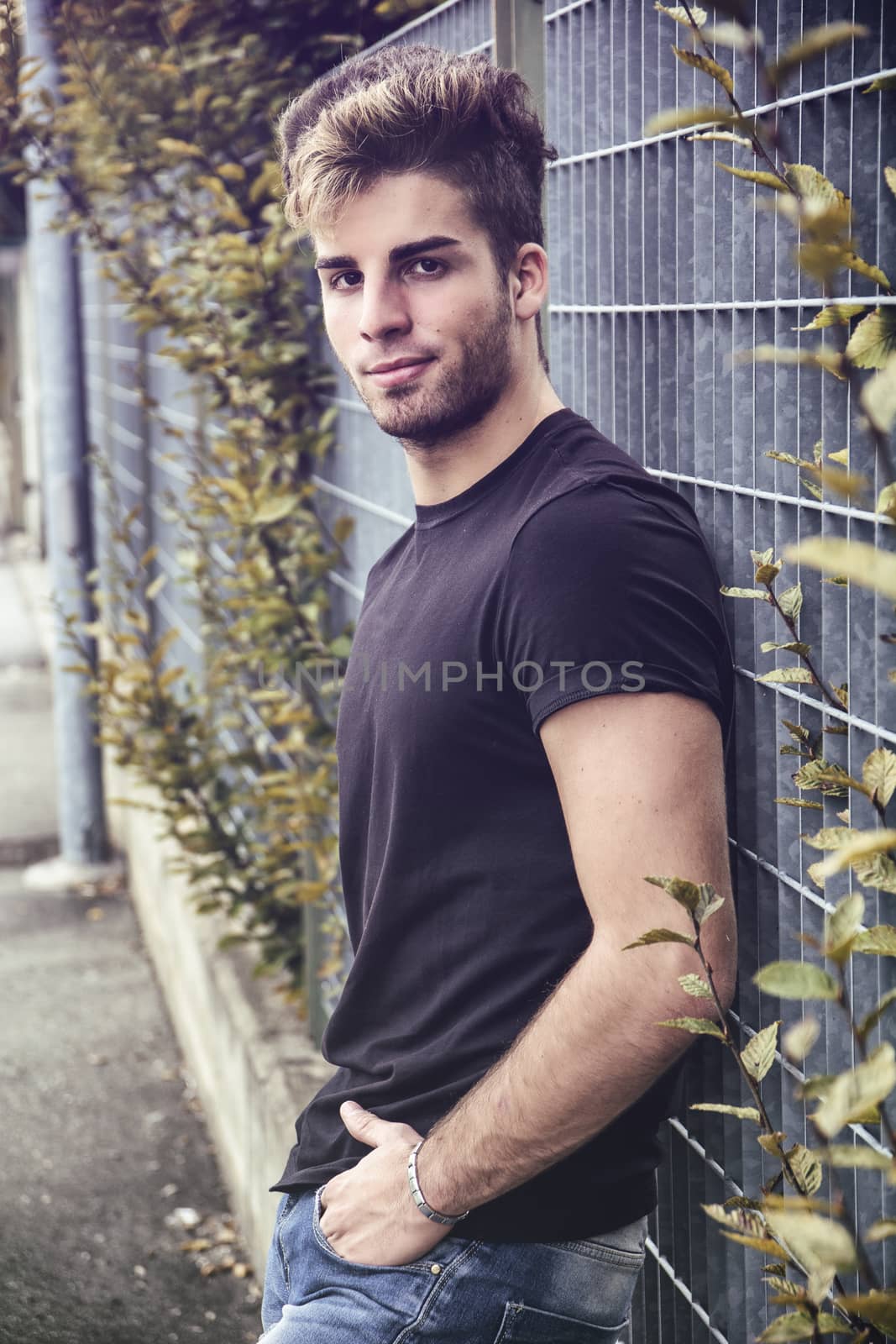 Attractive smiling man standing by city street looking at camera