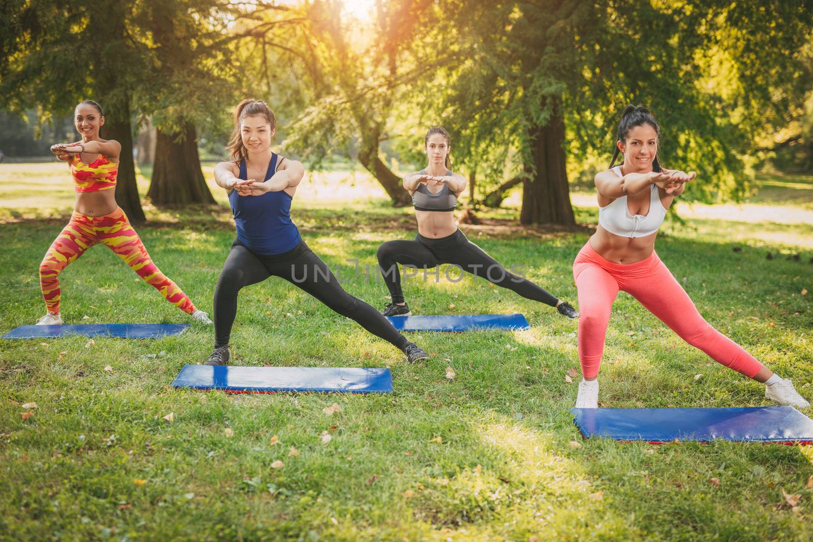 Four beautiful female friends doing exercise in the park. 