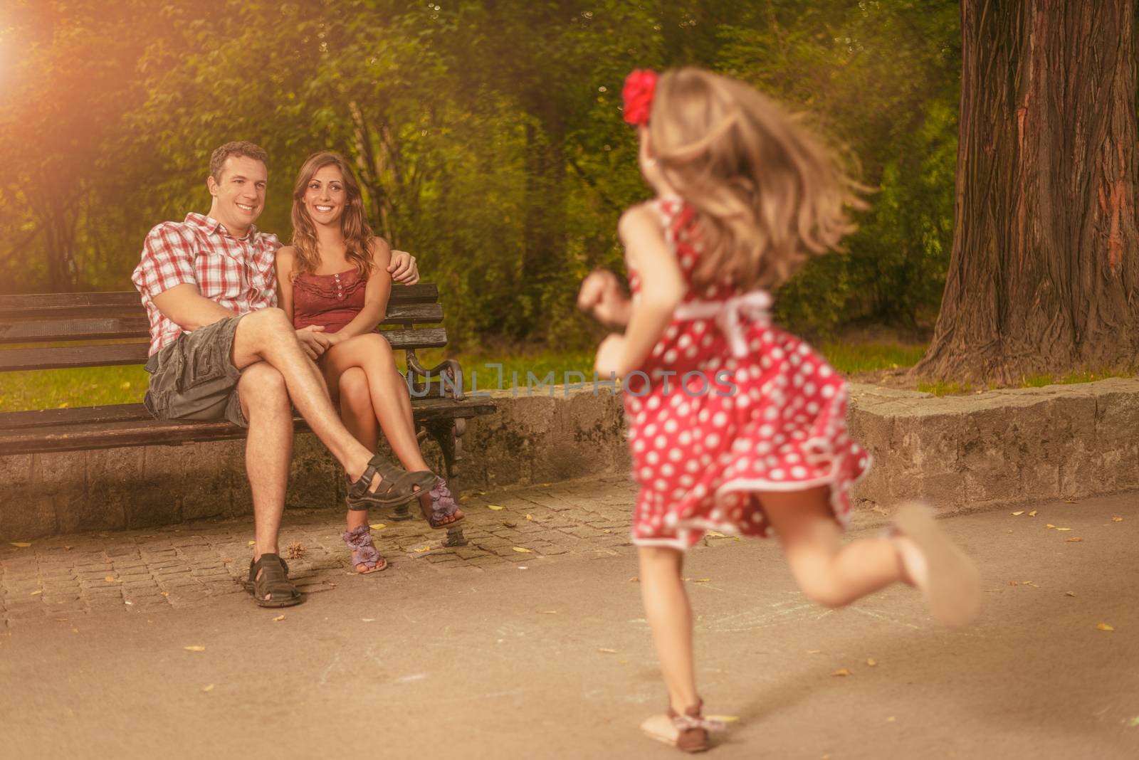 Beautiful little girl race to her parents in the park.