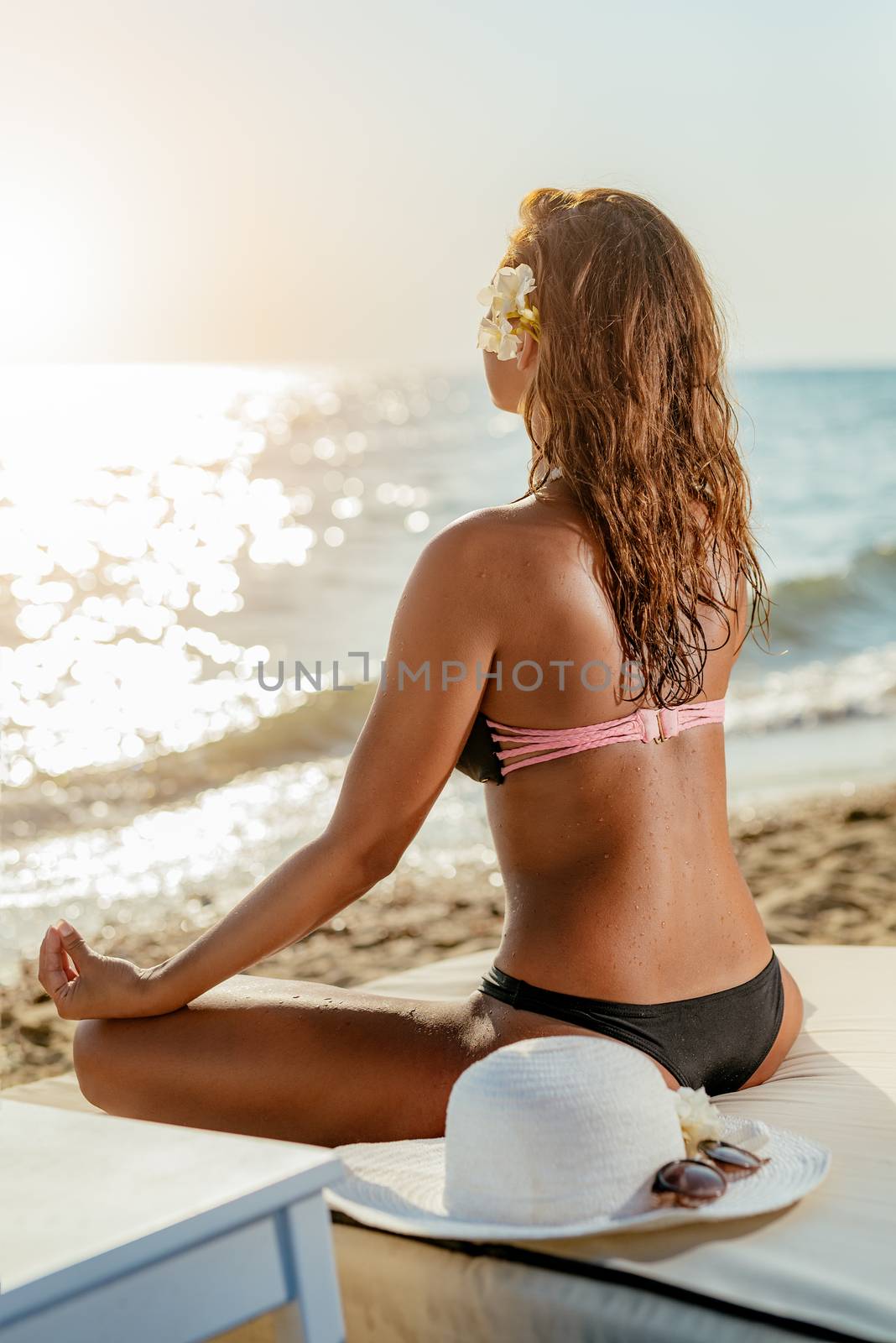 Beautiful young woman doing yoga on the beach.