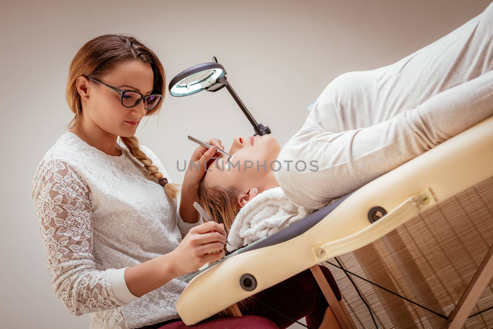 Beautician applying extended eyelashes to model at the beauty salon.