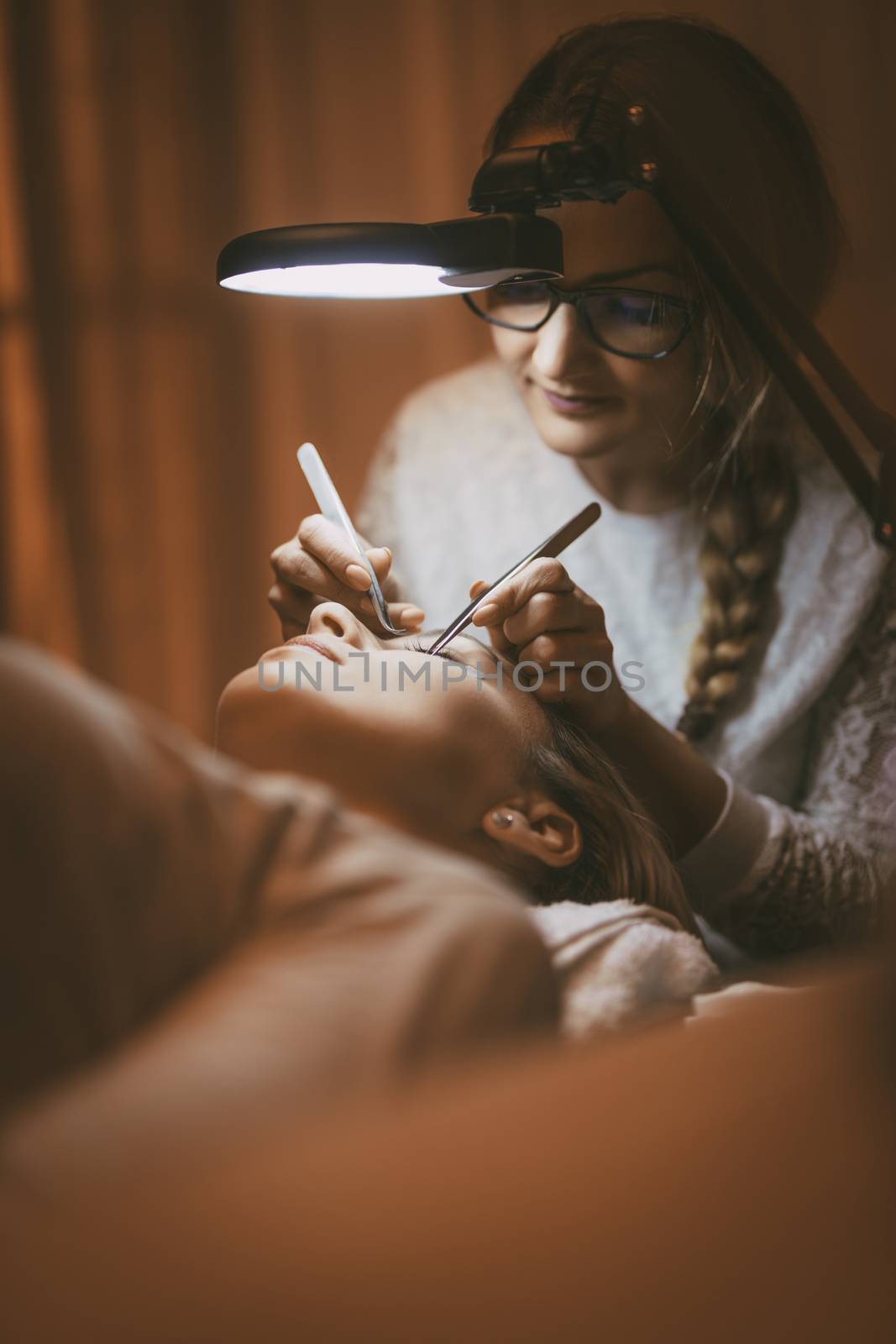 Beautician applying extended eyelashes to model. 