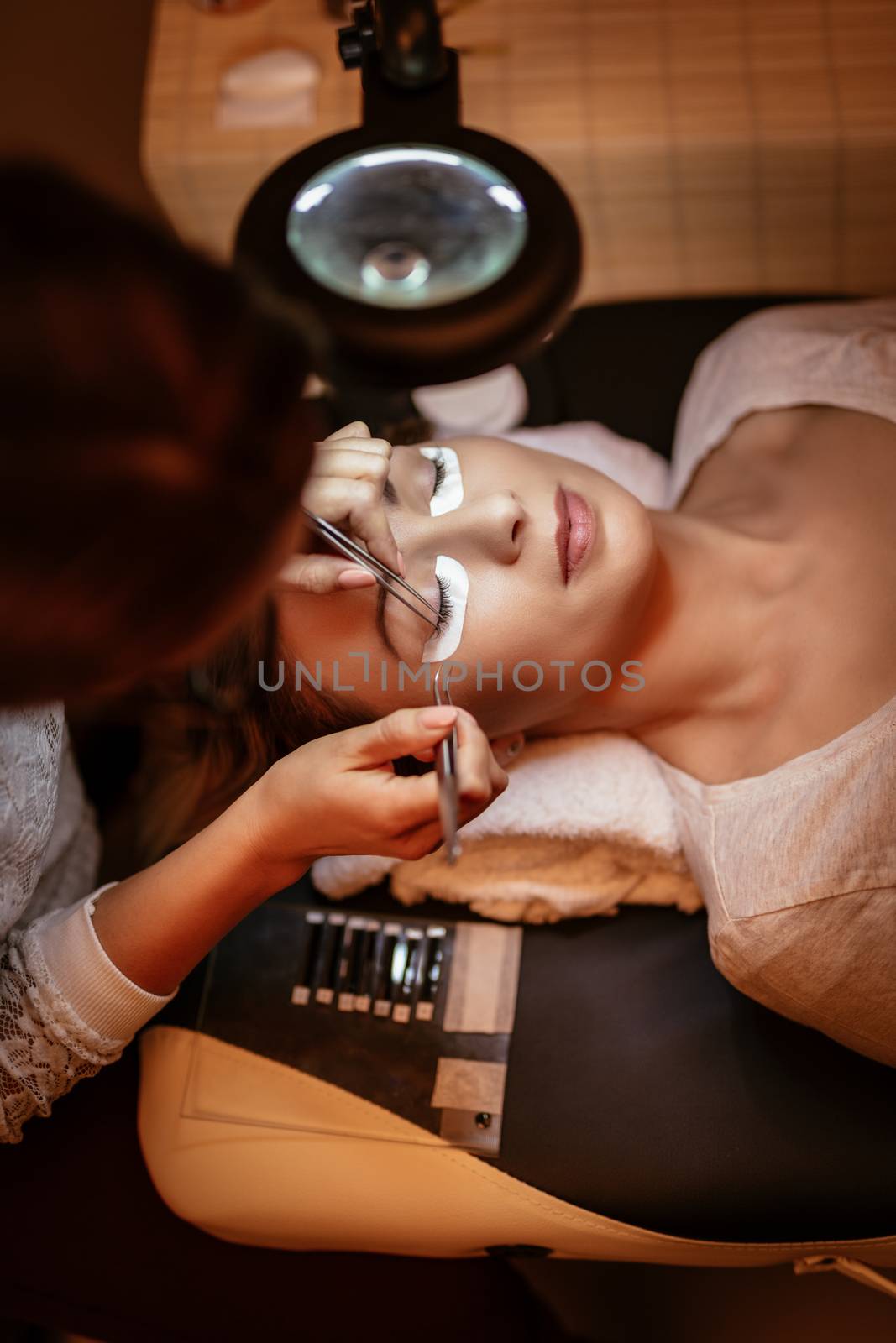 Beautician applying extended eyelashes to model at the beauty salon.