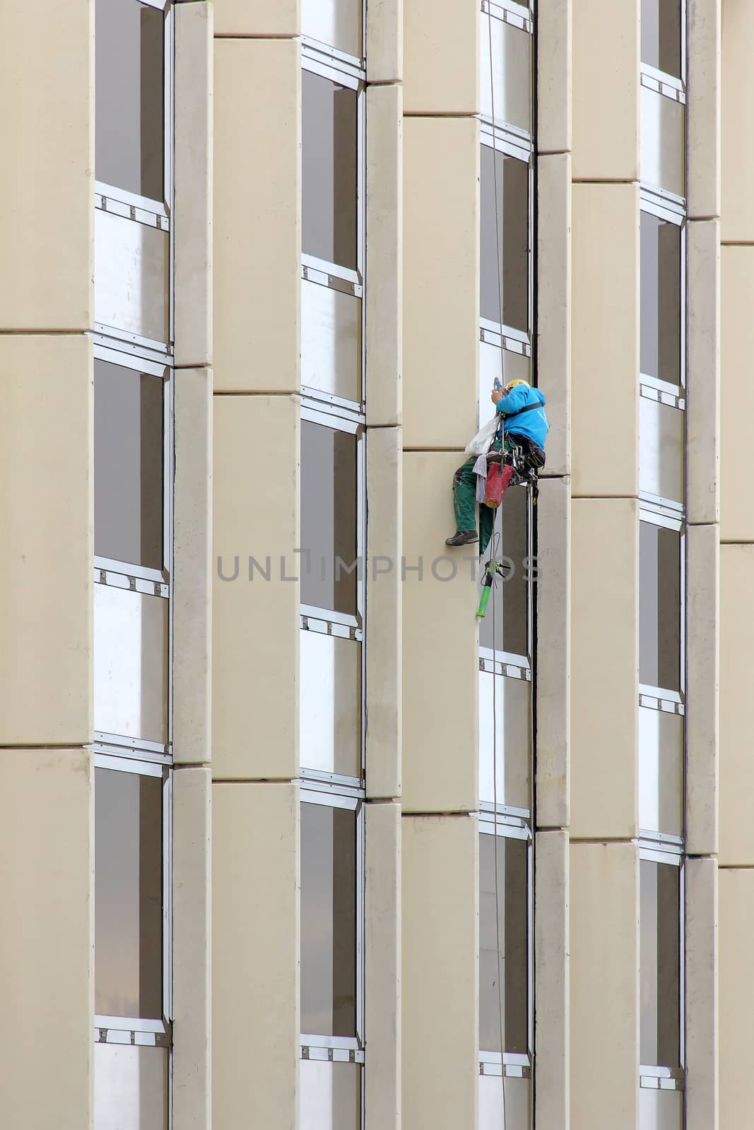 Alpinist window cleaning office building facade hanging cable ..