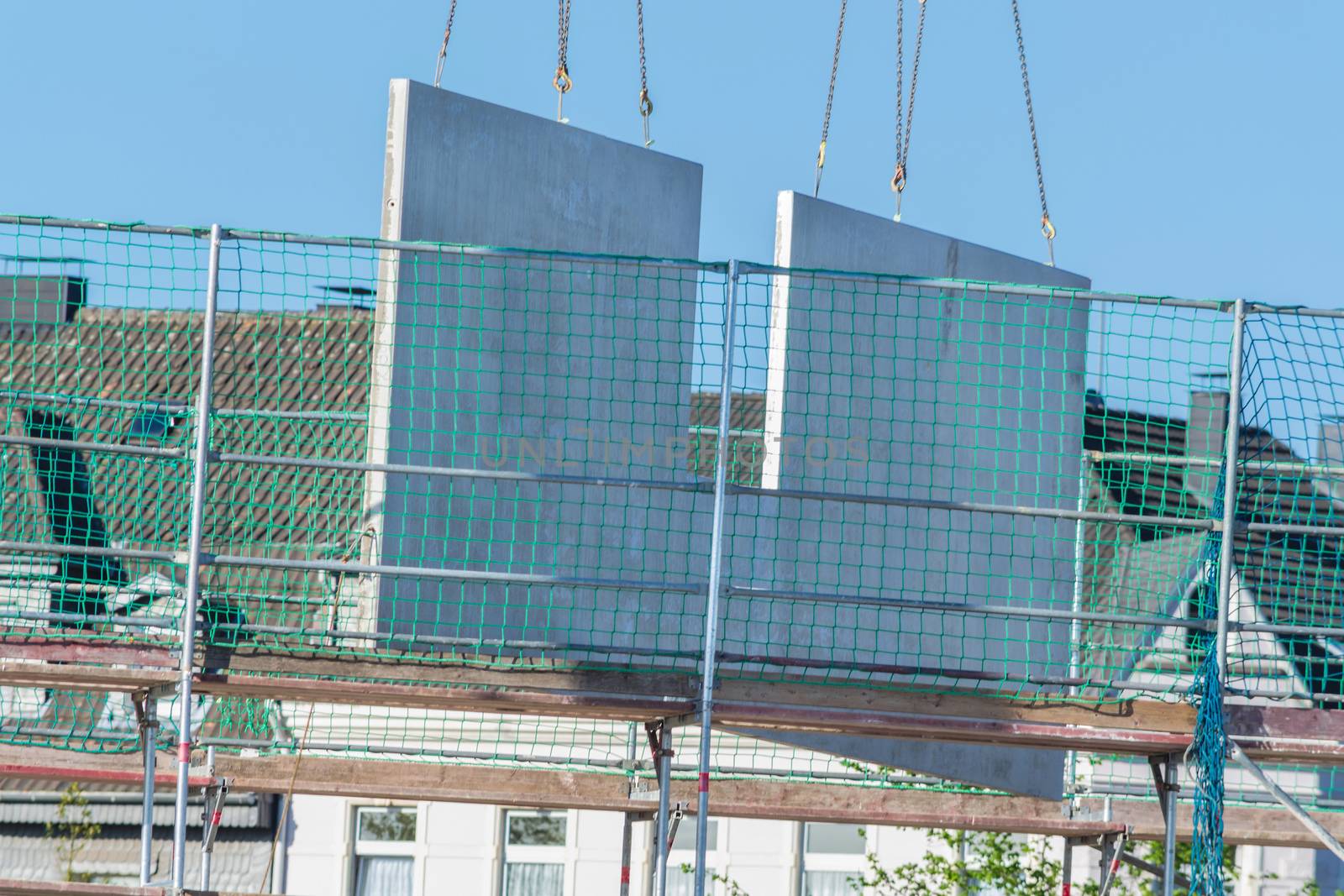 A precast concrete wall on a crane on a construction site. For the construction of prefabricated houses.