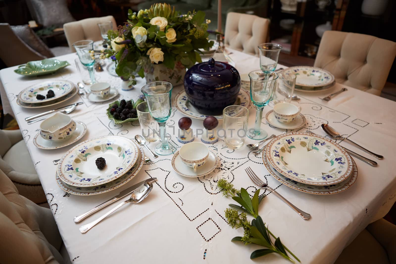 Decorated table ready for dinner. Beautifully decorated table set with flowers, candles, plates and serviettes for wedding or another event in the restaurant.