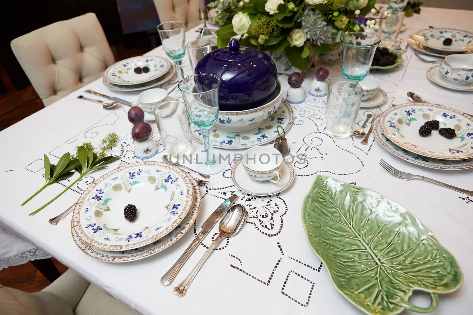 Decorated table ready for dinner. Beautifully decorated table set with flowers, candles, plates and serviettes for wedding or another event in the restaurant.