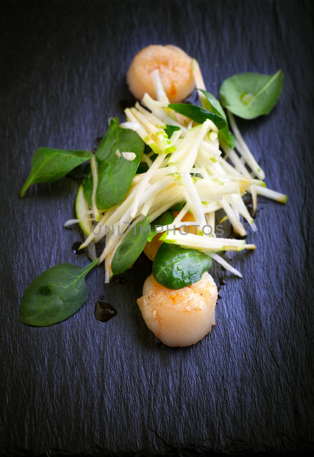 Scallop salad with apple, spinach on a stone plate 