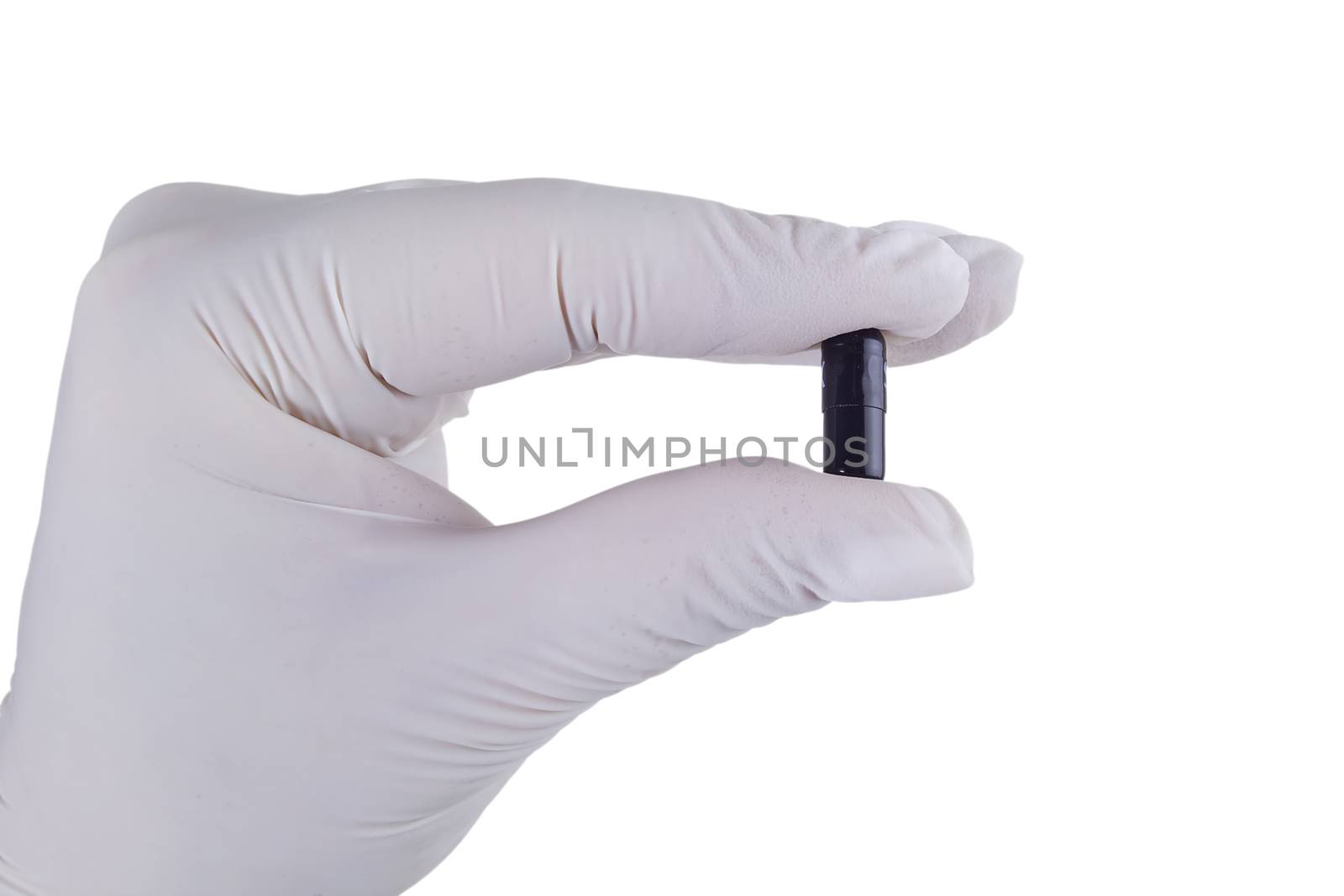 Hand in latex glove holding a pill on a white background