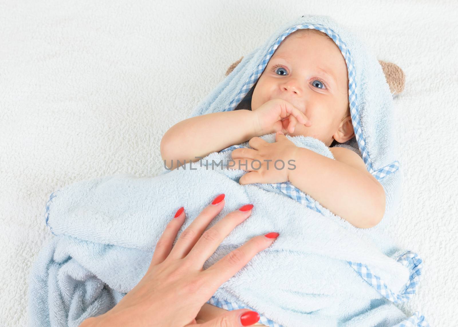 Cute happy beautiful smiling playful child boy with wet hair sitting in hothouse bath light blue fluffy towel white background, horizontal photo.