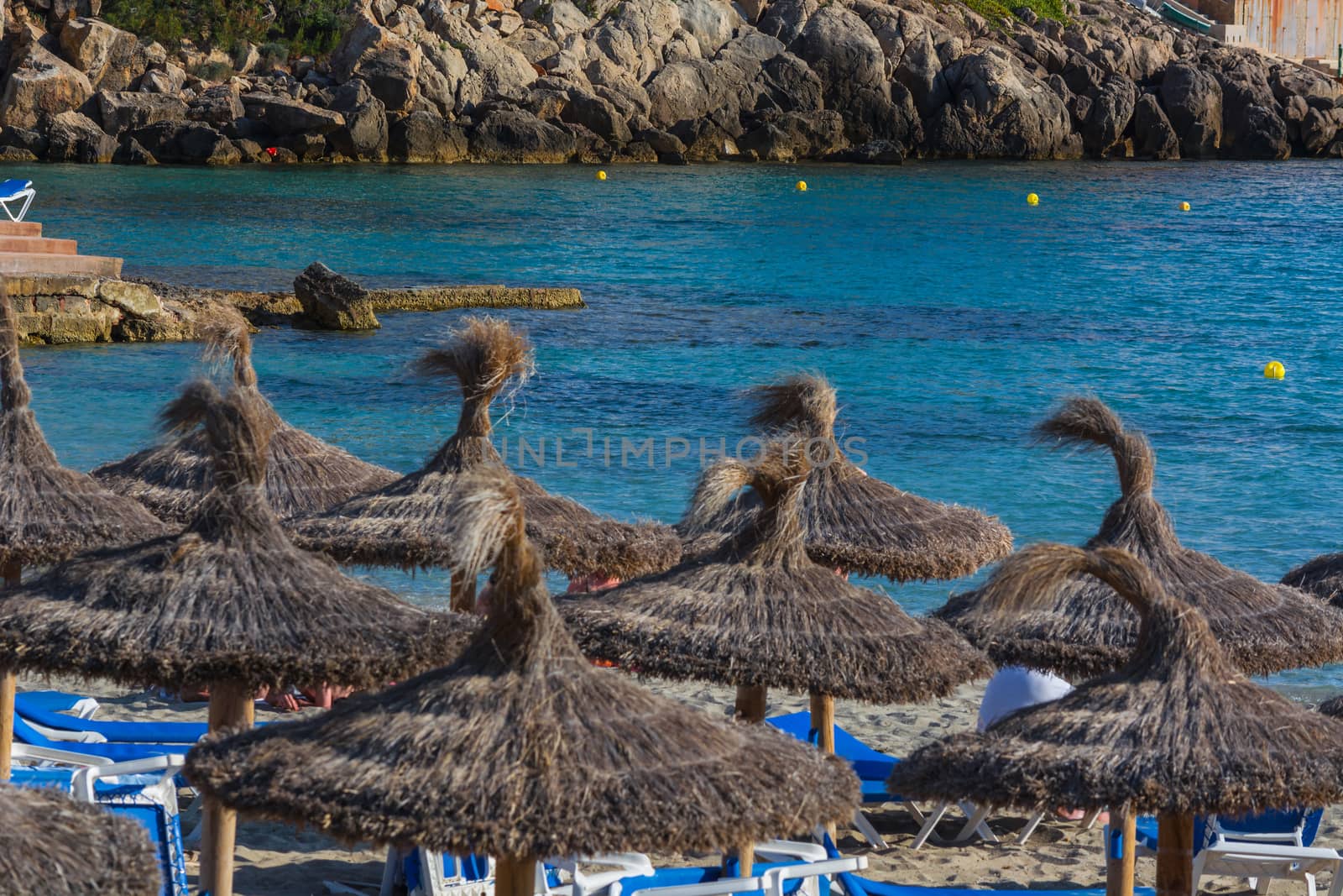 Blue sea and sand beach with sun loungers and parasols.
