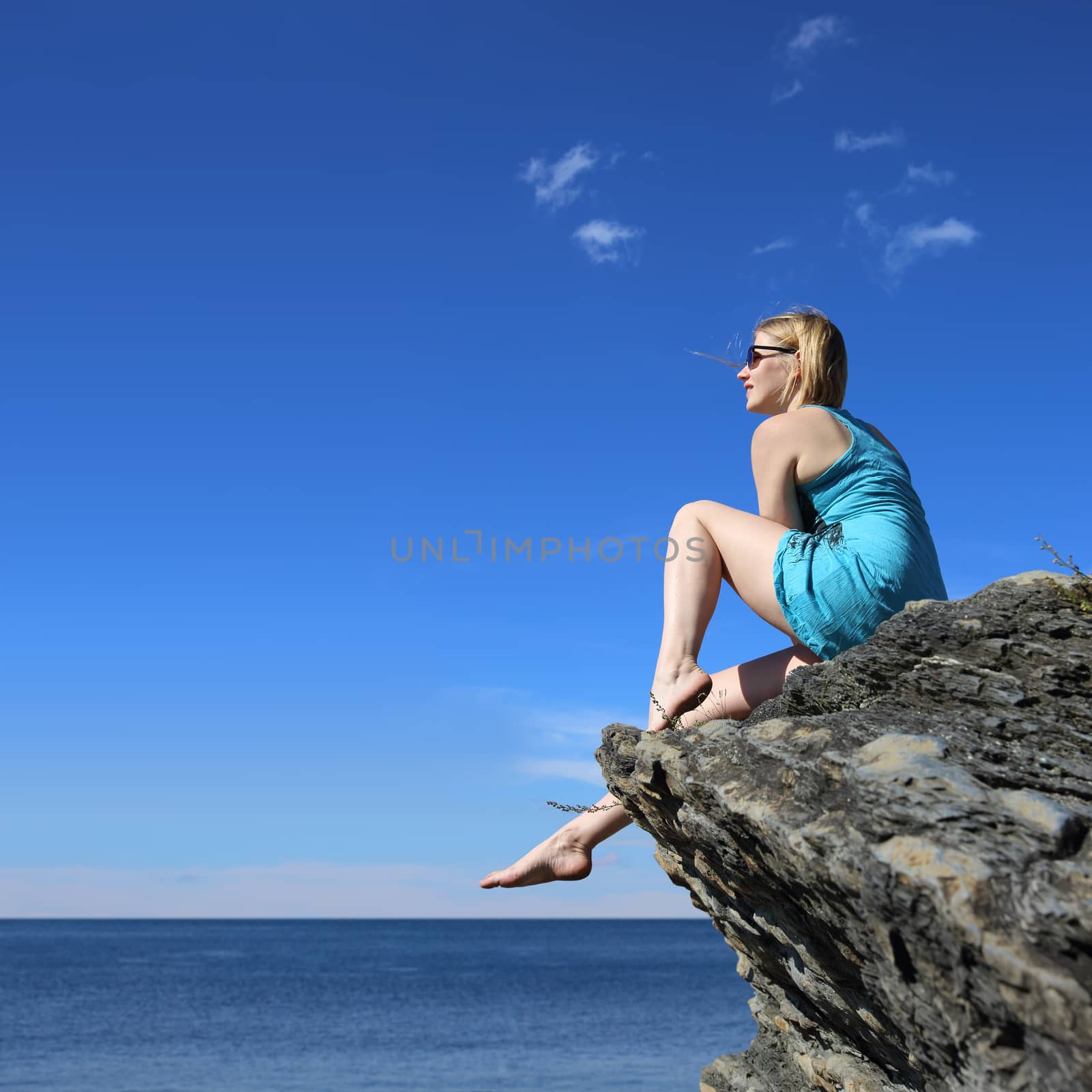 Woman sitting on rock , looking at ocean, vacation concept