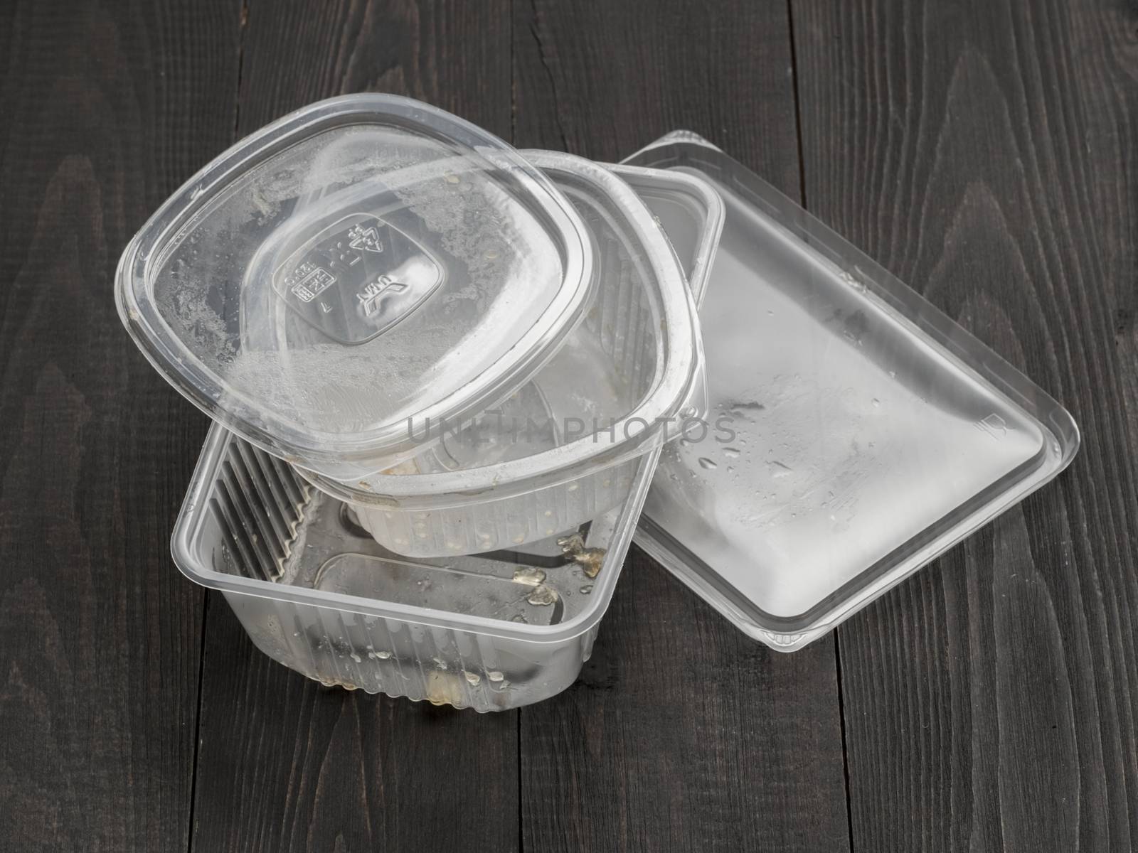 Dirty plastic food container on dark wooden background by fascinadora