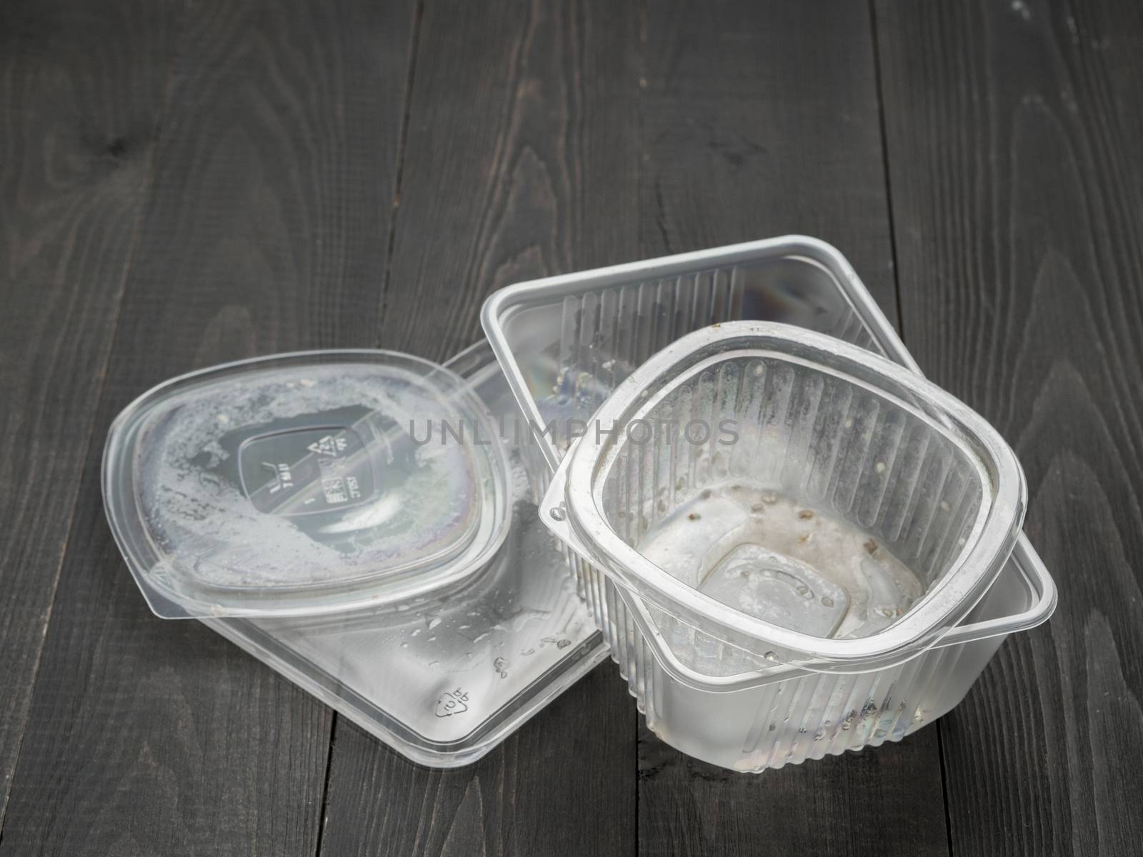 Dirty plastic food container on dark wooden background by fascinadora