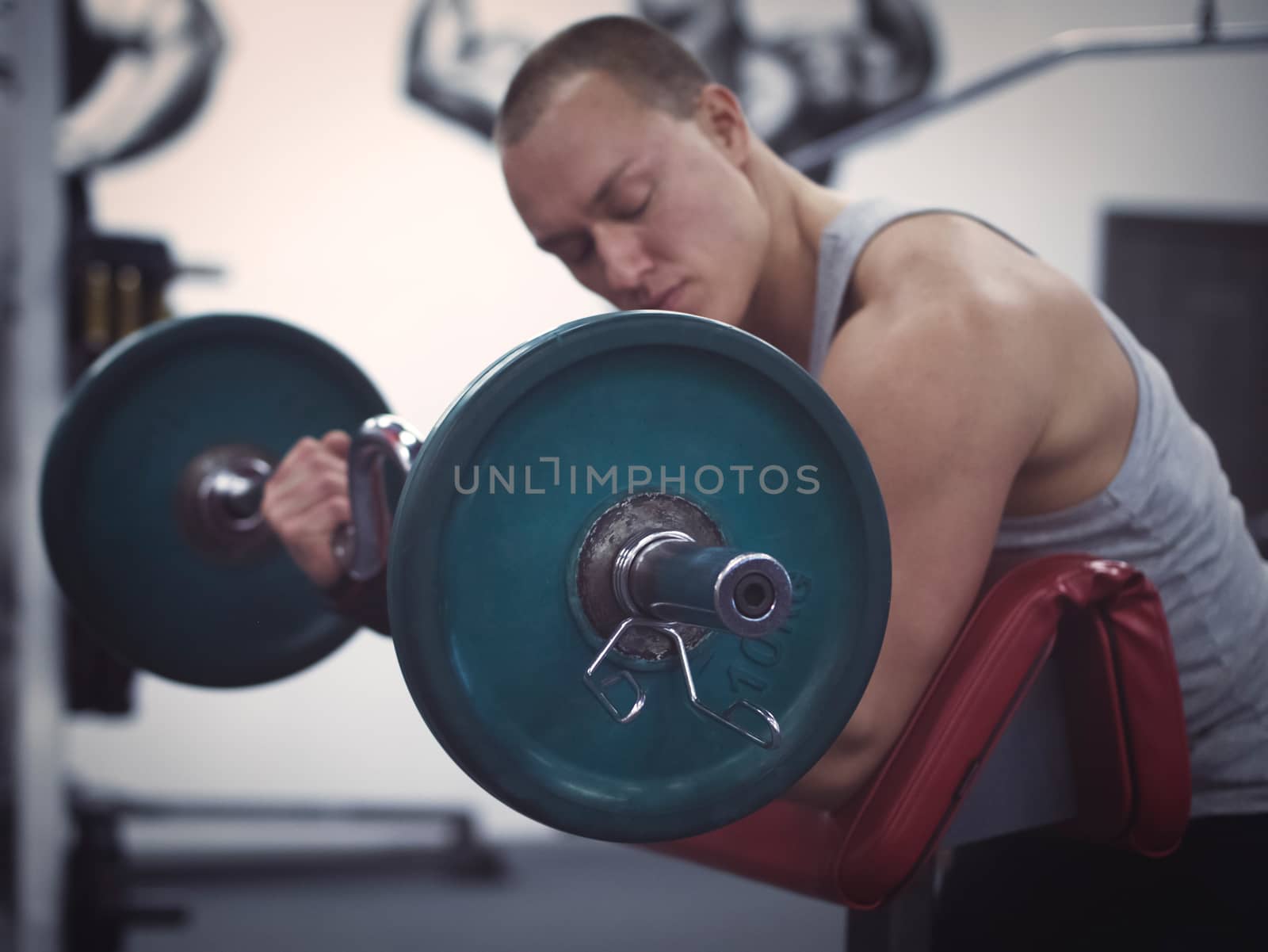 side view of muscular man holding barbell in gym. Focus on barbell. Training in gym concept. Toned image. Low key. Shallow DOF